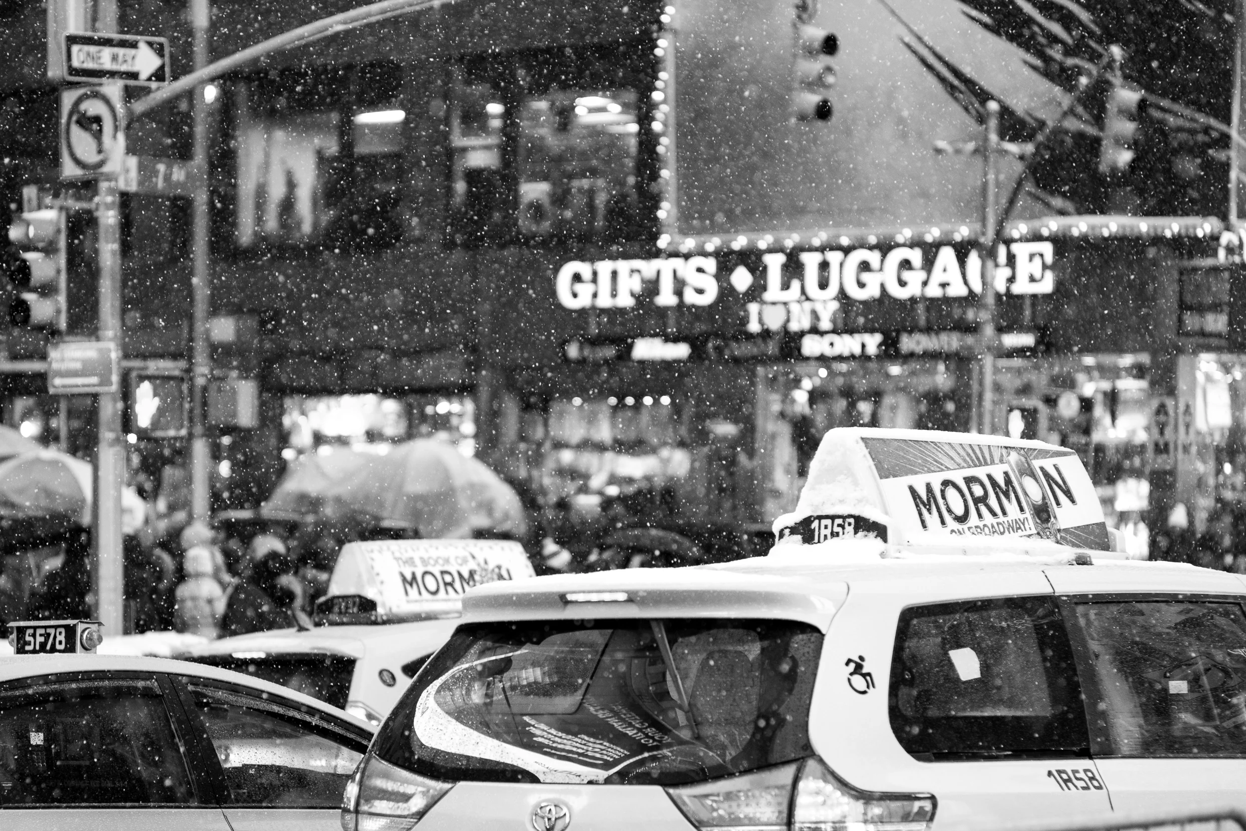 Taxi cabs lined up on the streets of Times Square during a late evening snowfall