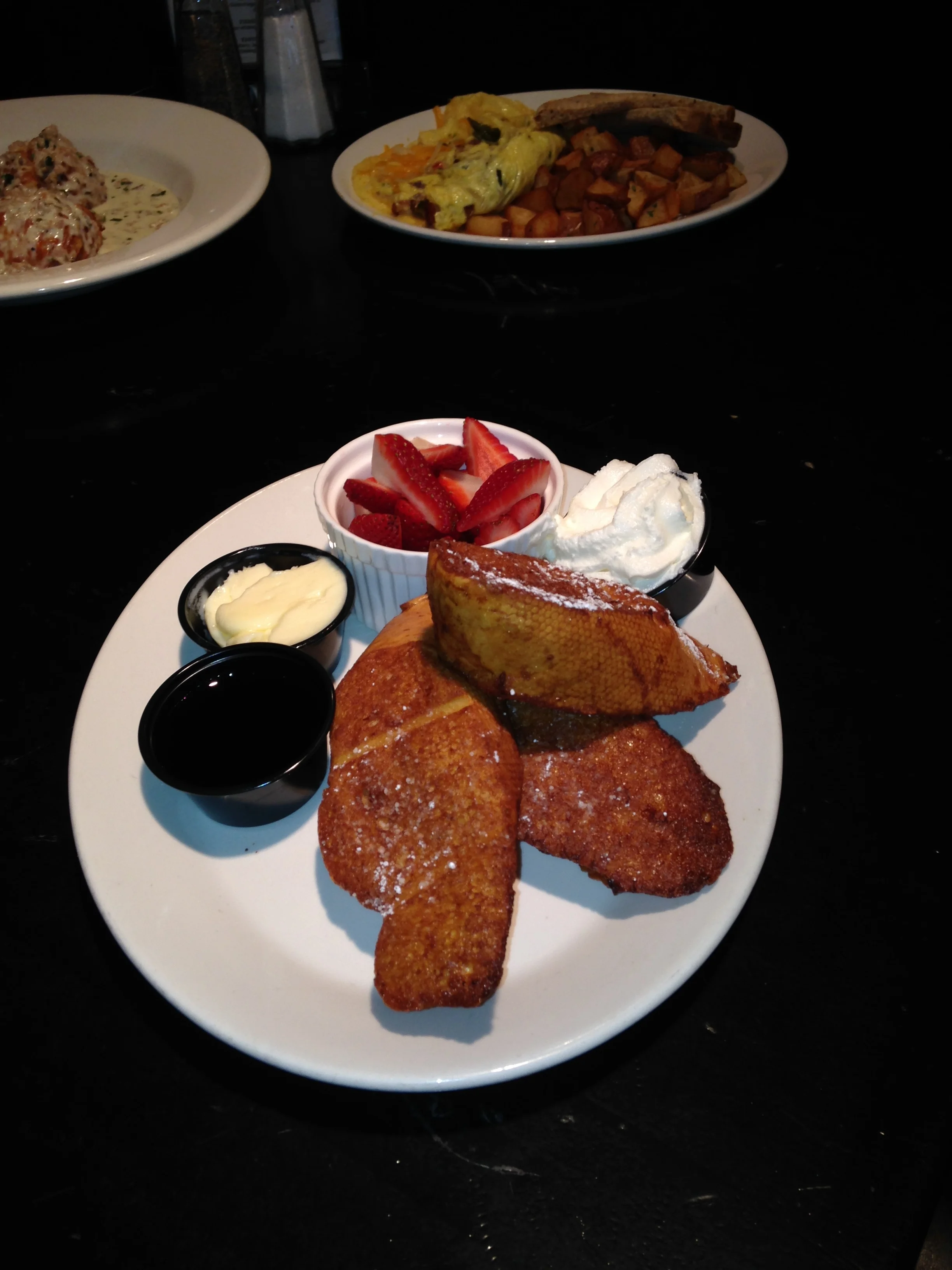 French toast! Thick pieces of challah, fried golden brown & topped with powdered sugar. Have it with fresh berries and whipped cream!