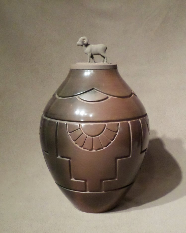Brown Shadow Colored Storage Jar with Bighorn Sheep Ram lid This piece is based by the Kiva Step design, It includes fans of feathers and the clouds above. 14-1/4" H X 9-1/4" Dia