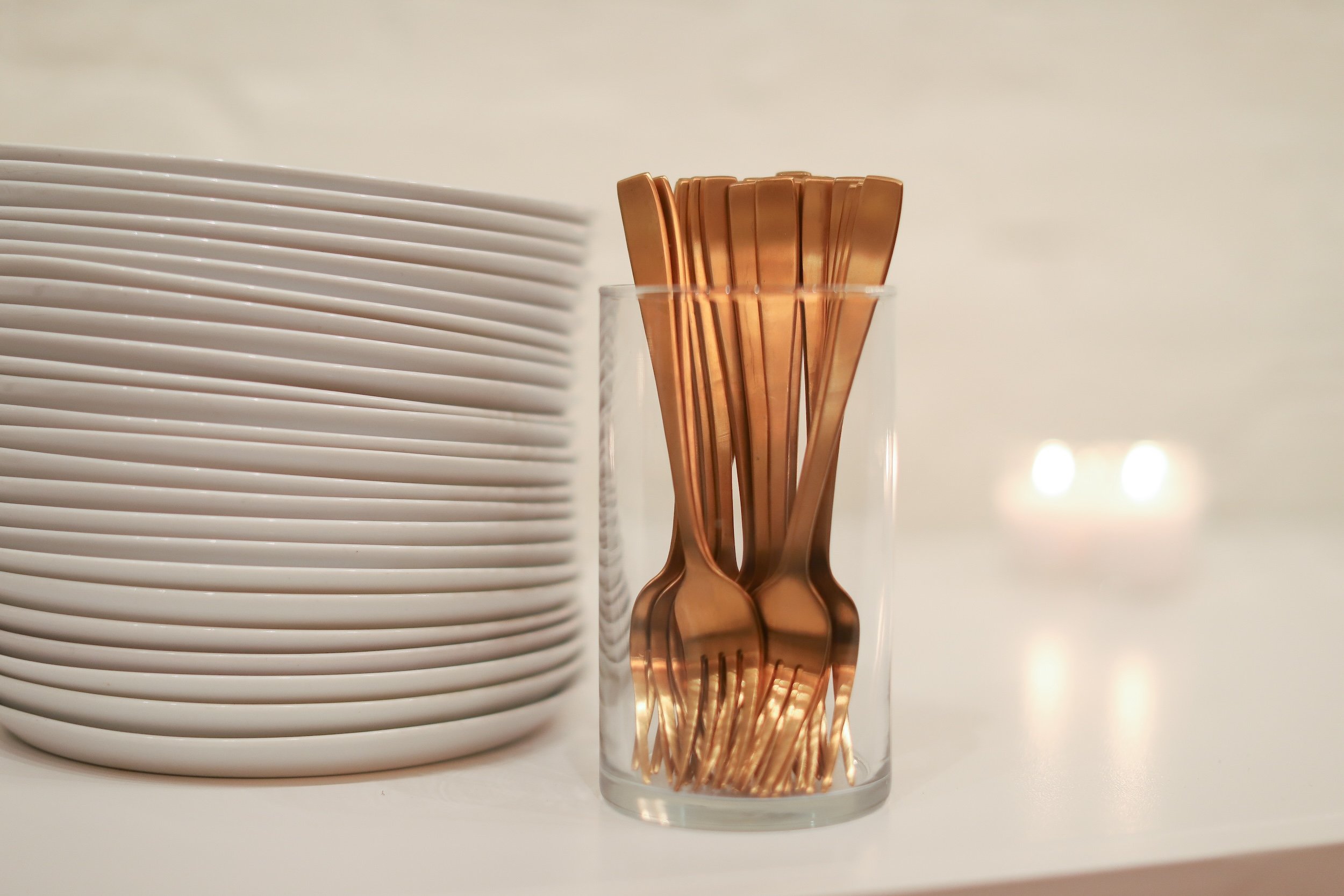 Gold forks in a glass next to plates.jpg