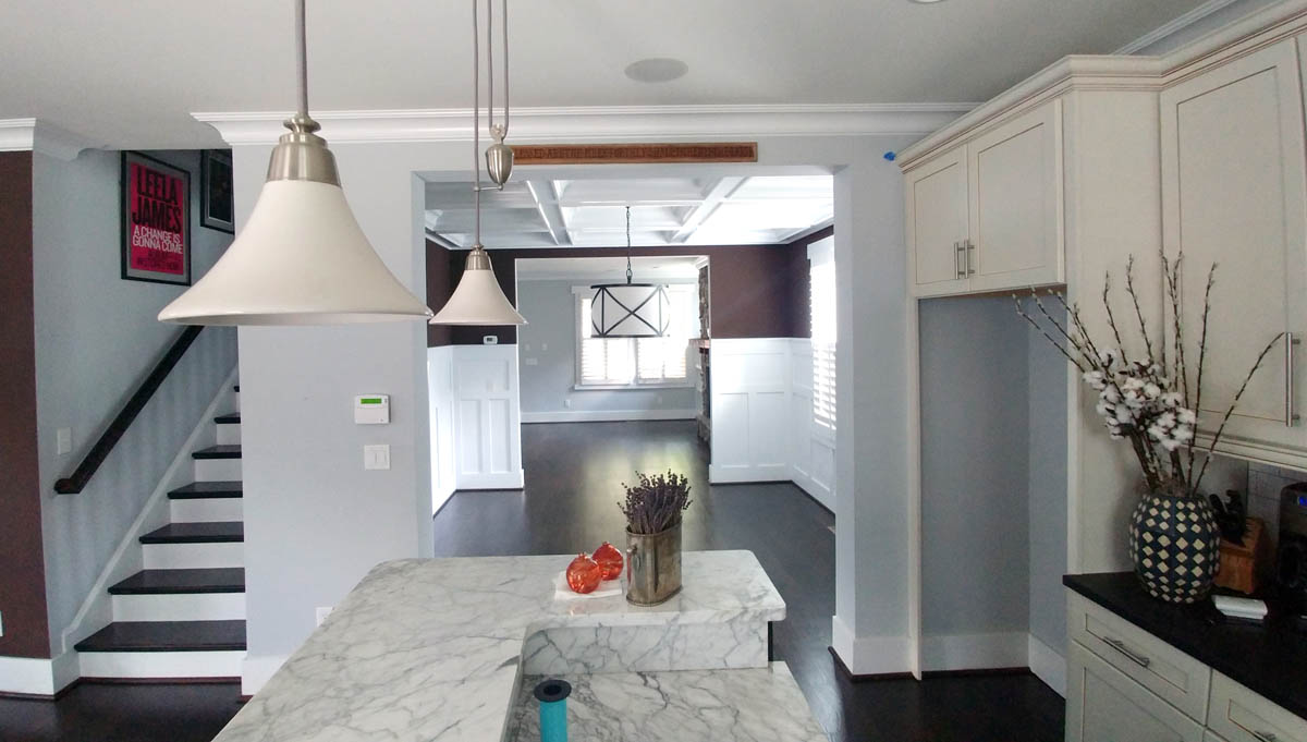 Stunning Kitchen renovation with marble, multi-height island, dark floors, and a fresh color palette for cabinets and walls.