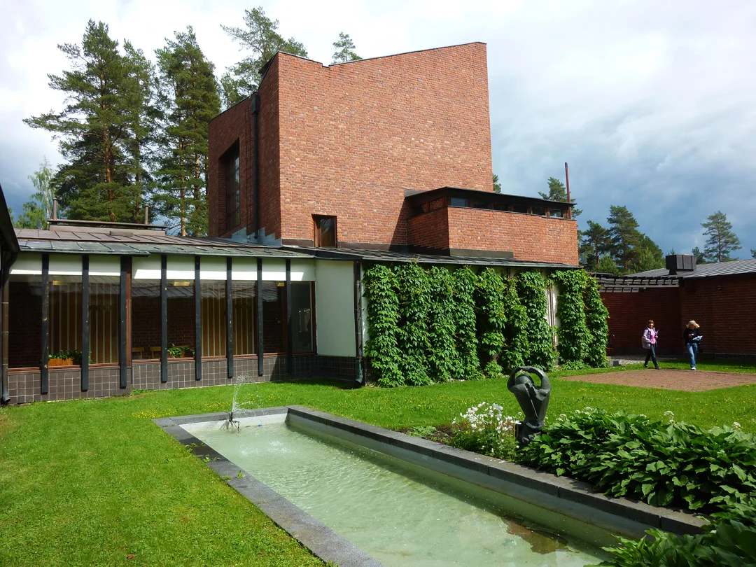 A view of the delightful contrast of the brick-clad tower of the council chamber with the grass-covered courtyard garden, with a fountain and sculpture in the middle. A series of meeting rooms and offices surround the hallway filled with natural light on the left. Source: Aseem Inam.