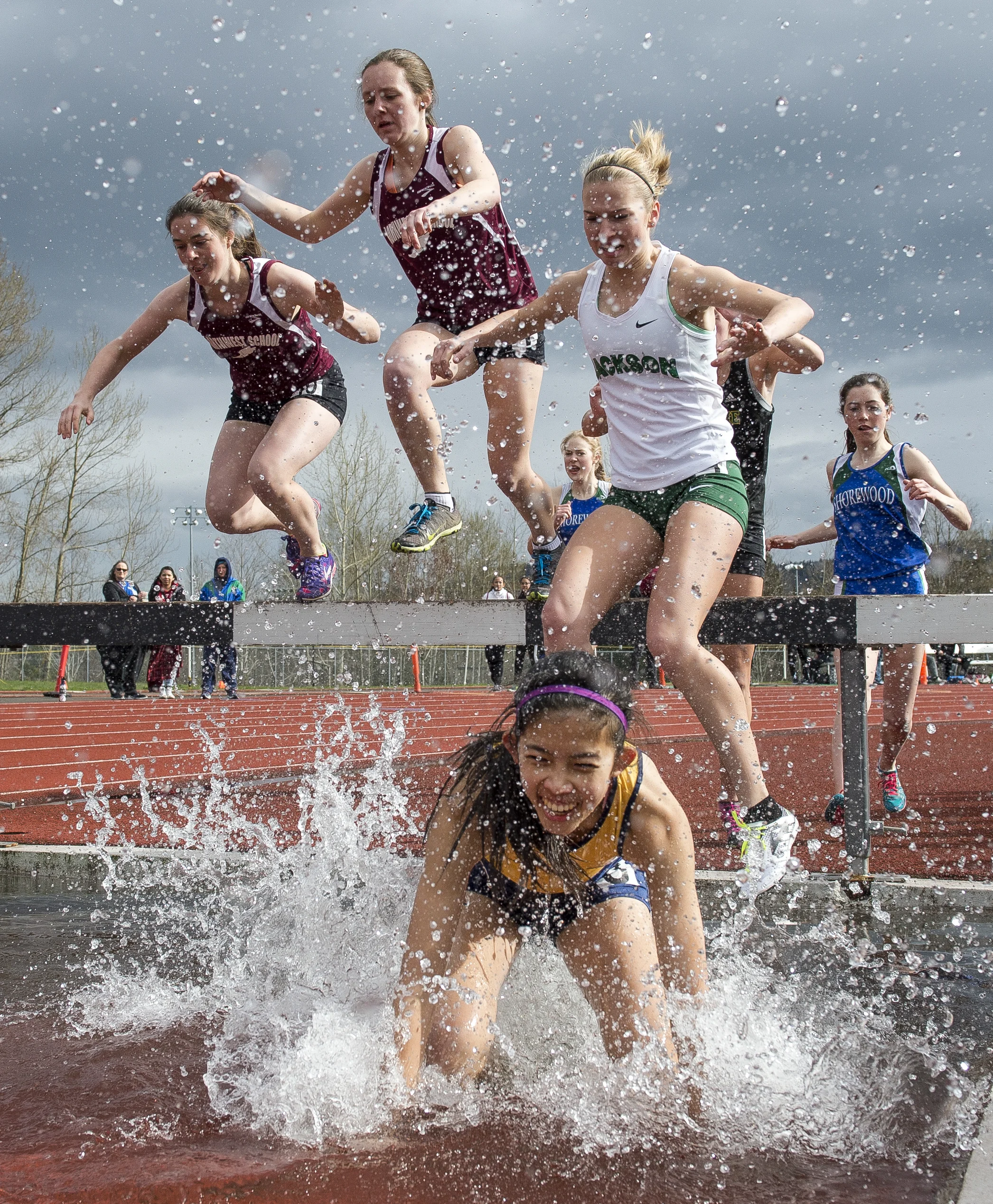  Girls splash through the water obstacle of the 2k steeplechase at the Birger Solberg Invitational on Saturday, April 8, at Civic Stadium in Bellingham.&nbsp; 