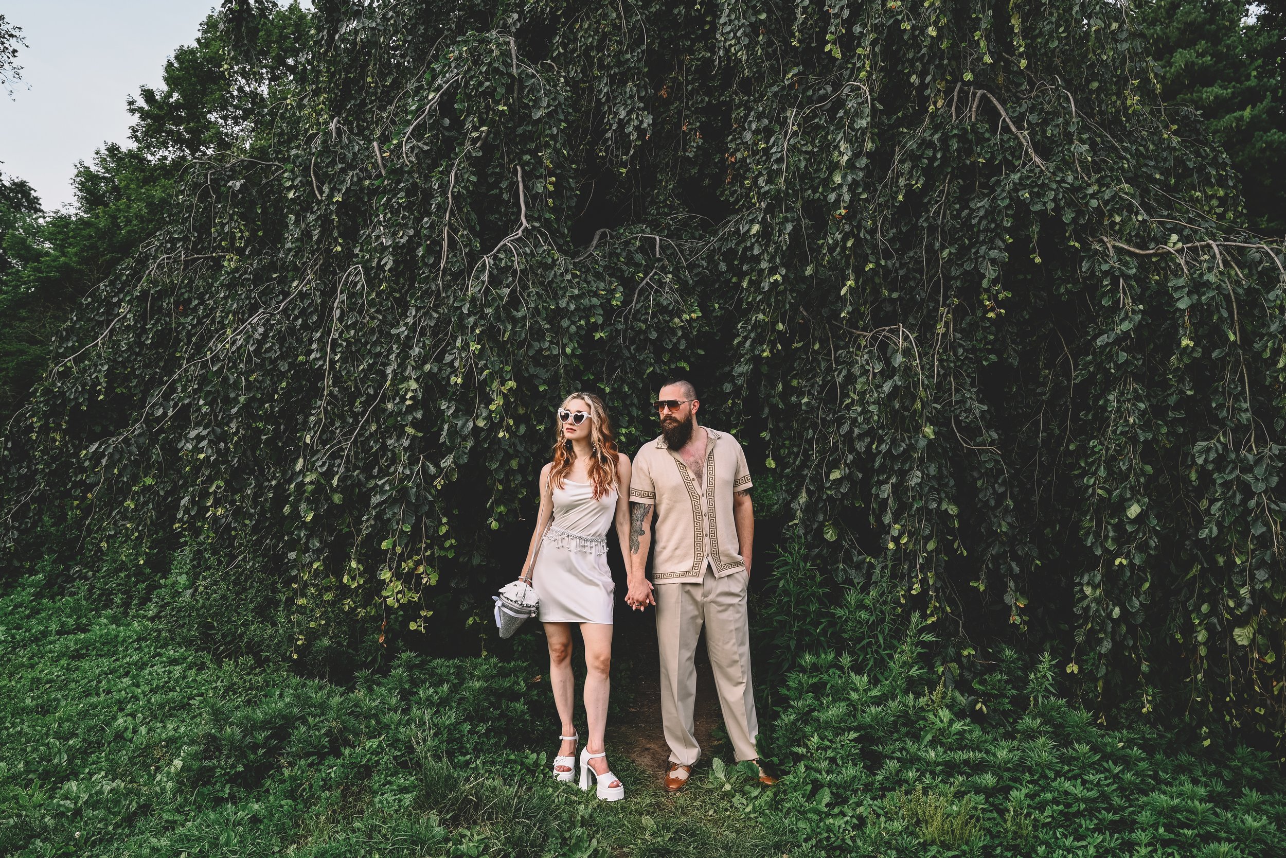 Prospect Park engagement session in Brooklyn featuring a couple walking beneath lush greenery, captured in a cinematic editorial style by NYC engagement photographer Robert Carlo.