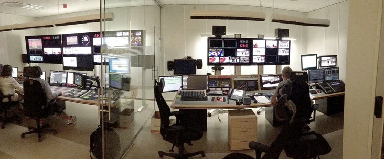 Regikontrollen, et eksternt kontrollpanel vekk fra studio der alt det tekniske pre-, direkte- og postproduksjon foregår. Hele regikontrollen, rommet t.v. sitter lydtekniker, bildemikser, grafikk, skript, produsent og andre teknisk personell, mens ommet t.h. sitter kamerakontroll og lystekniker. Foto: Tin Phan