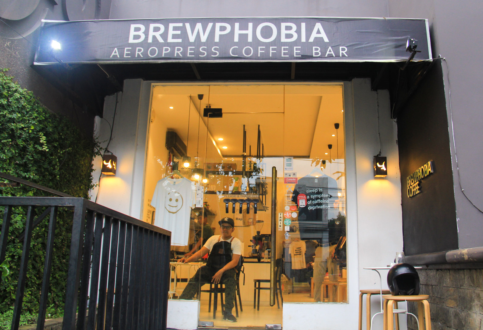 Mirza Luqman Effendy, founder of the Brewphobia coffee shop in South Jakarta, is seen through the window in his shop. Photo: Yosef Riadi for NPR