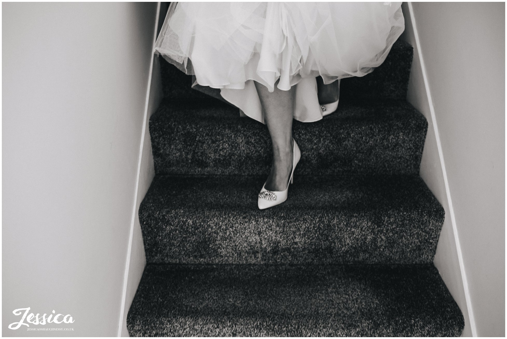 close up of brides feet as she walks down the stairs in her wedding dress