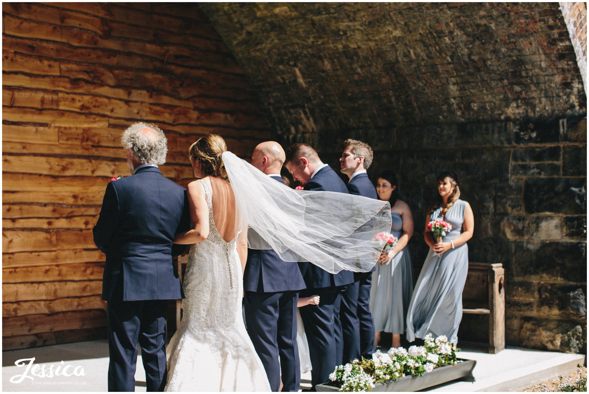 bride links arms with her father during the ceremony at her tower hill barns wedding