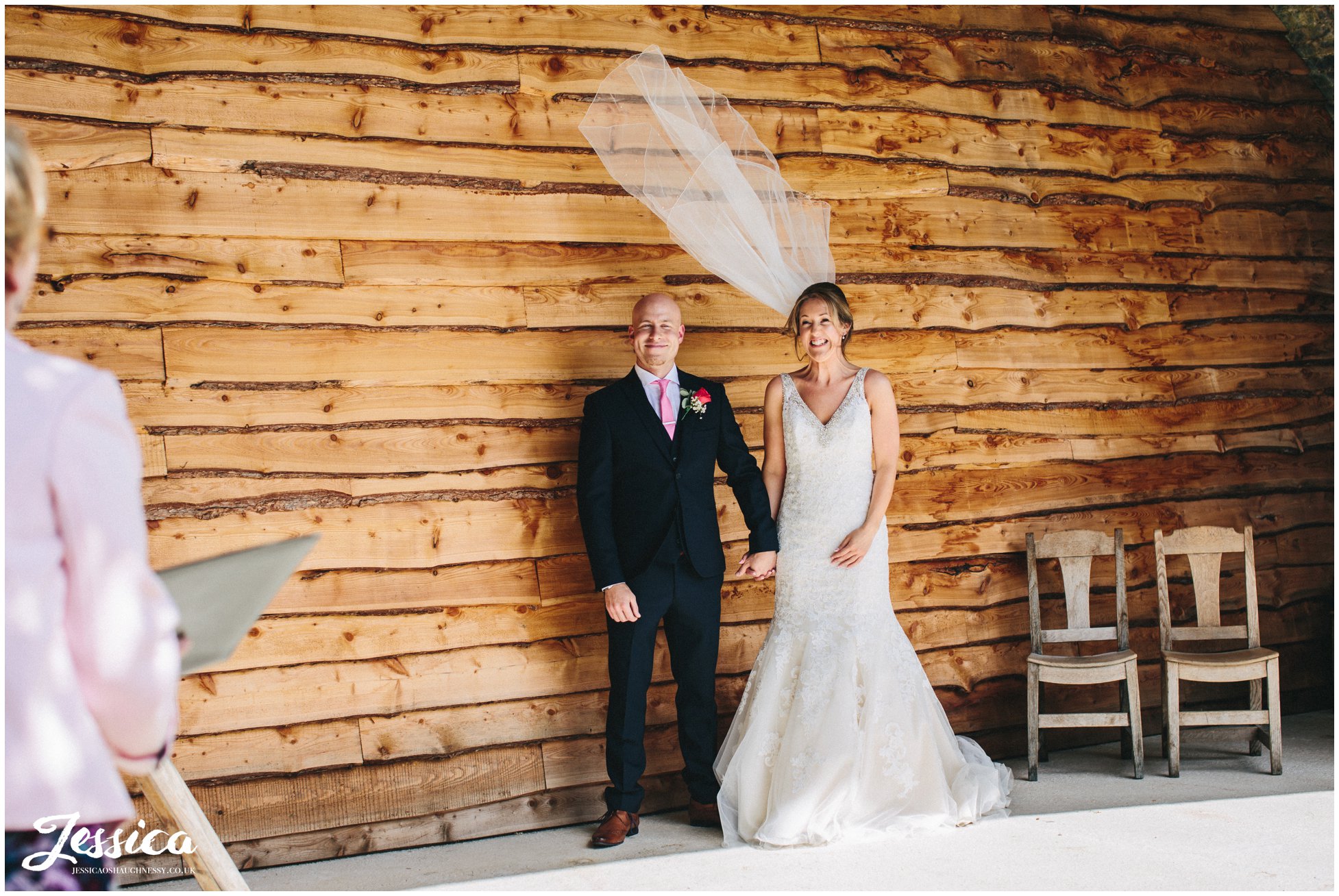 brides veil blows in the wind during their service under the bridge