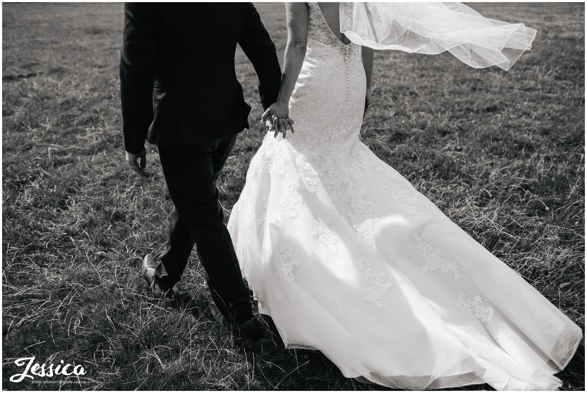 cropped black and white photograph of newly wed's walking through a field in north wales