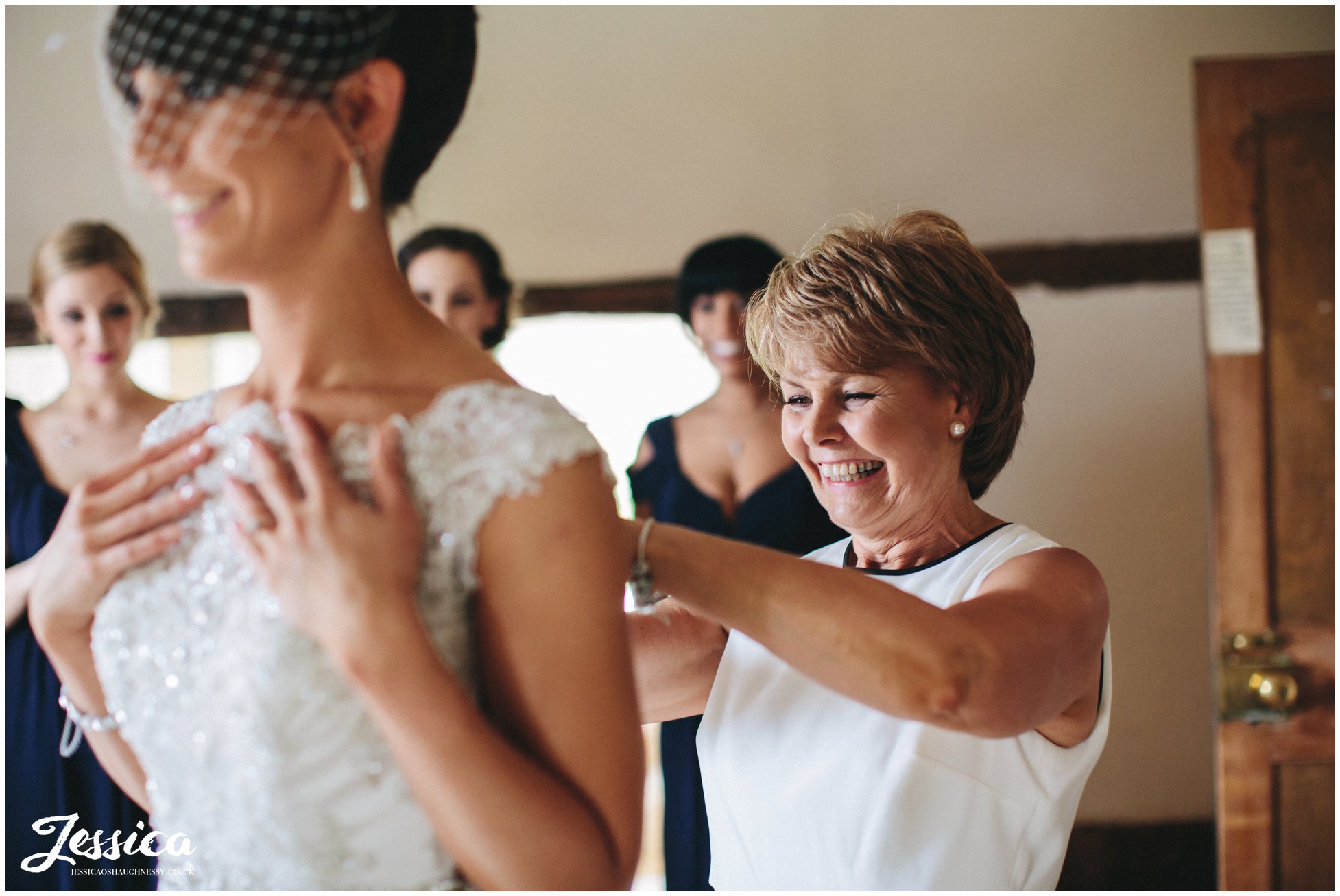 bride helped into her wedding dress by her mother at the mickle trafford manor - chester wedding photographer