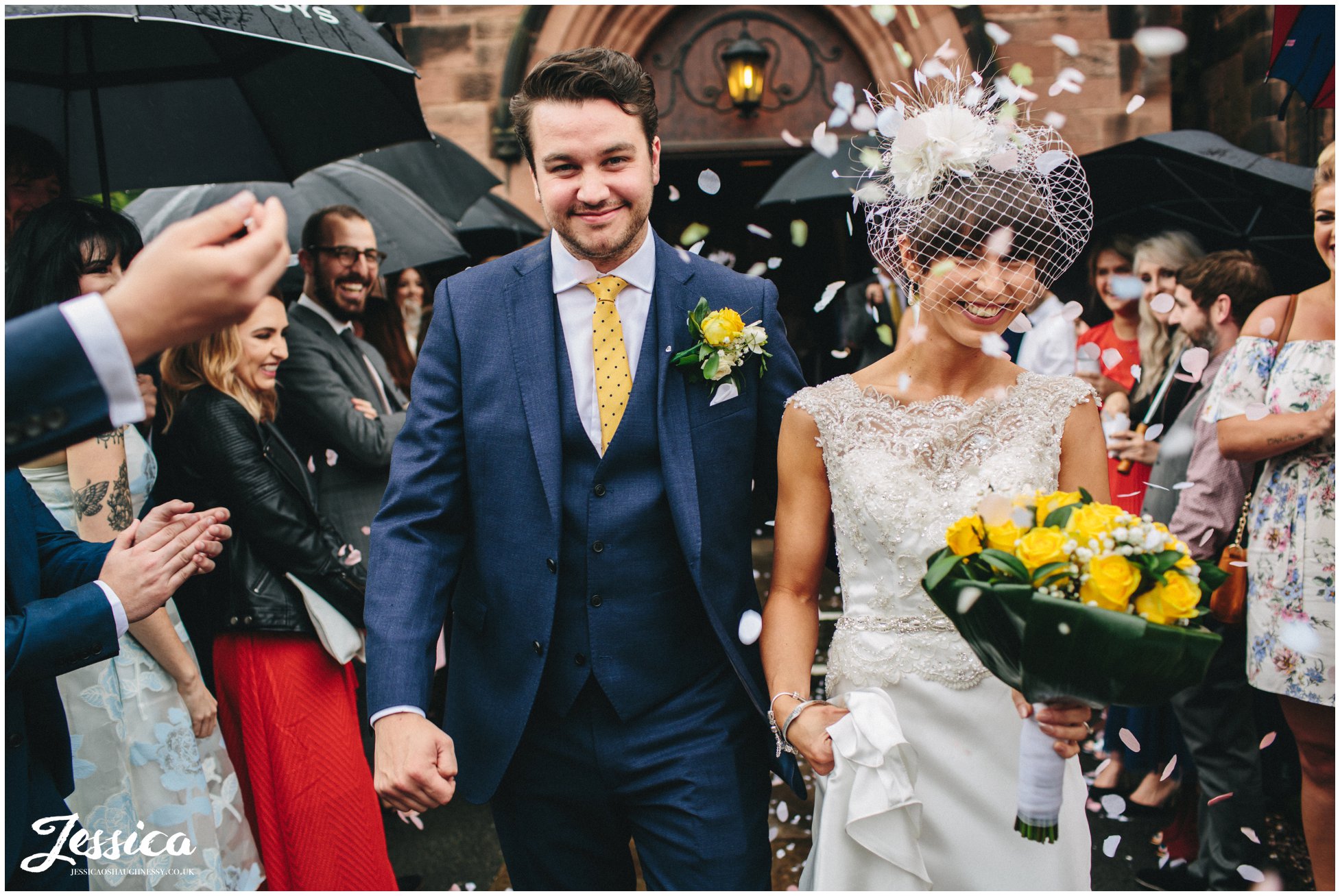 bride & groom walking through confetti line at Chester Church after their wedding