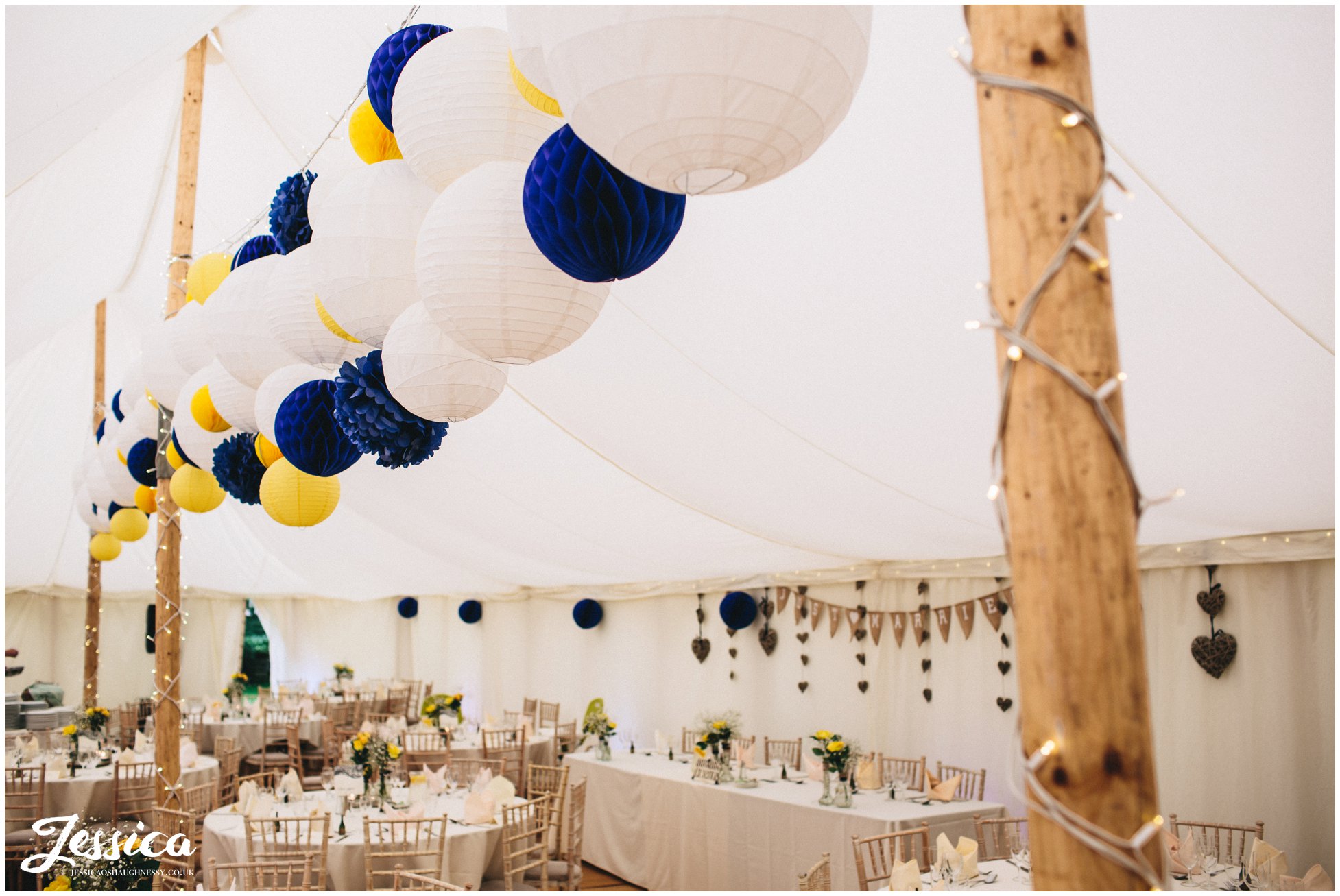 blue & yellow lanterns decorate the marquee at a wedding in trafford hall, chester