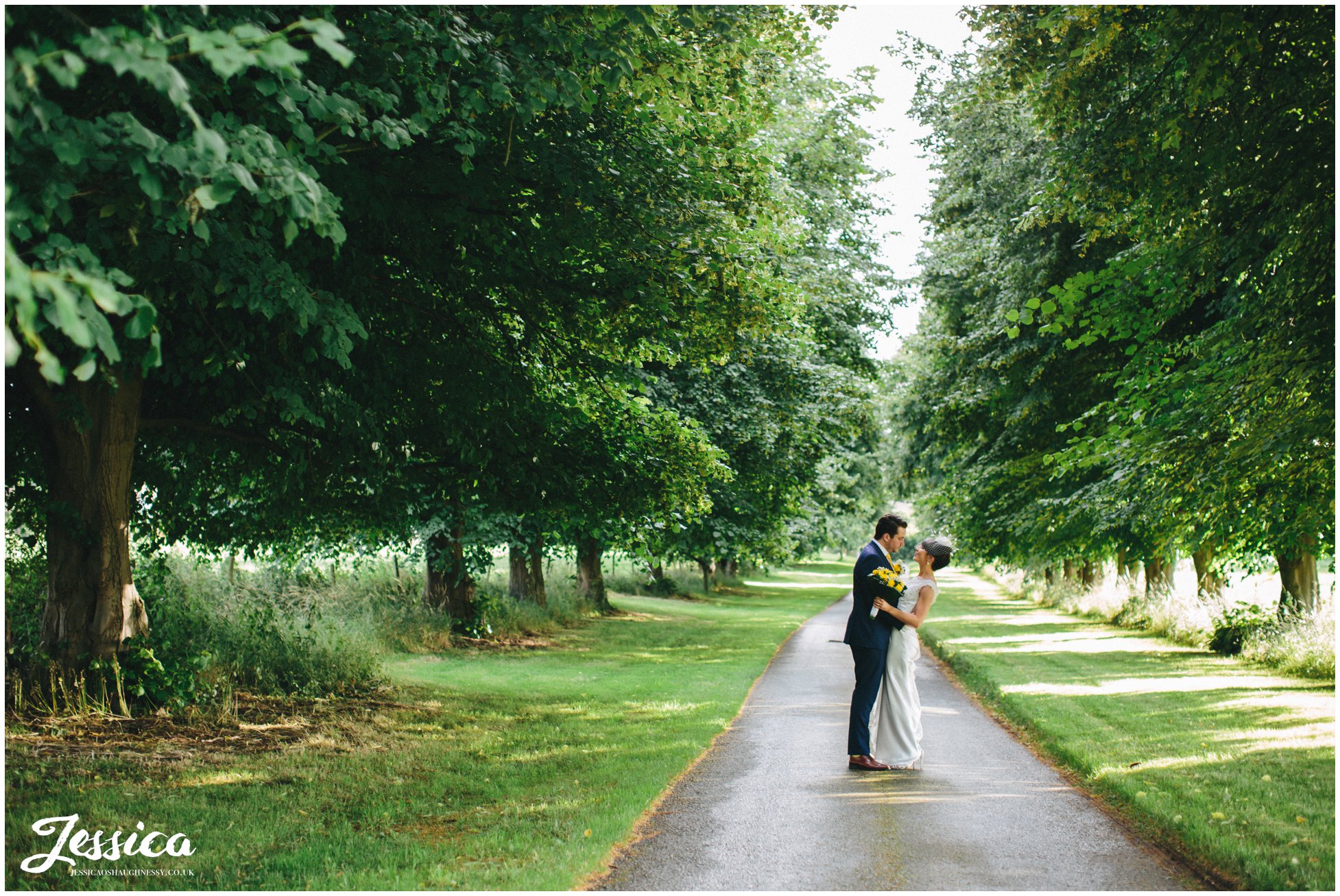 Bride & Groom standing between trees at Trafford Hall, Cheshire wedding photography