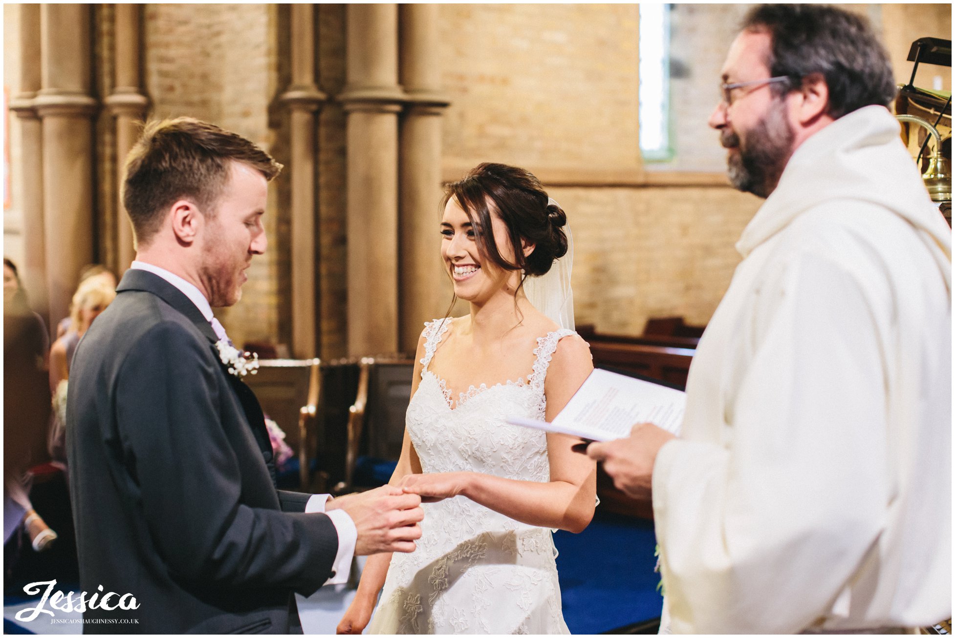 bride & groom exchange rings in St Bridget's church in Bridekirk, Cumbria wedding photographer