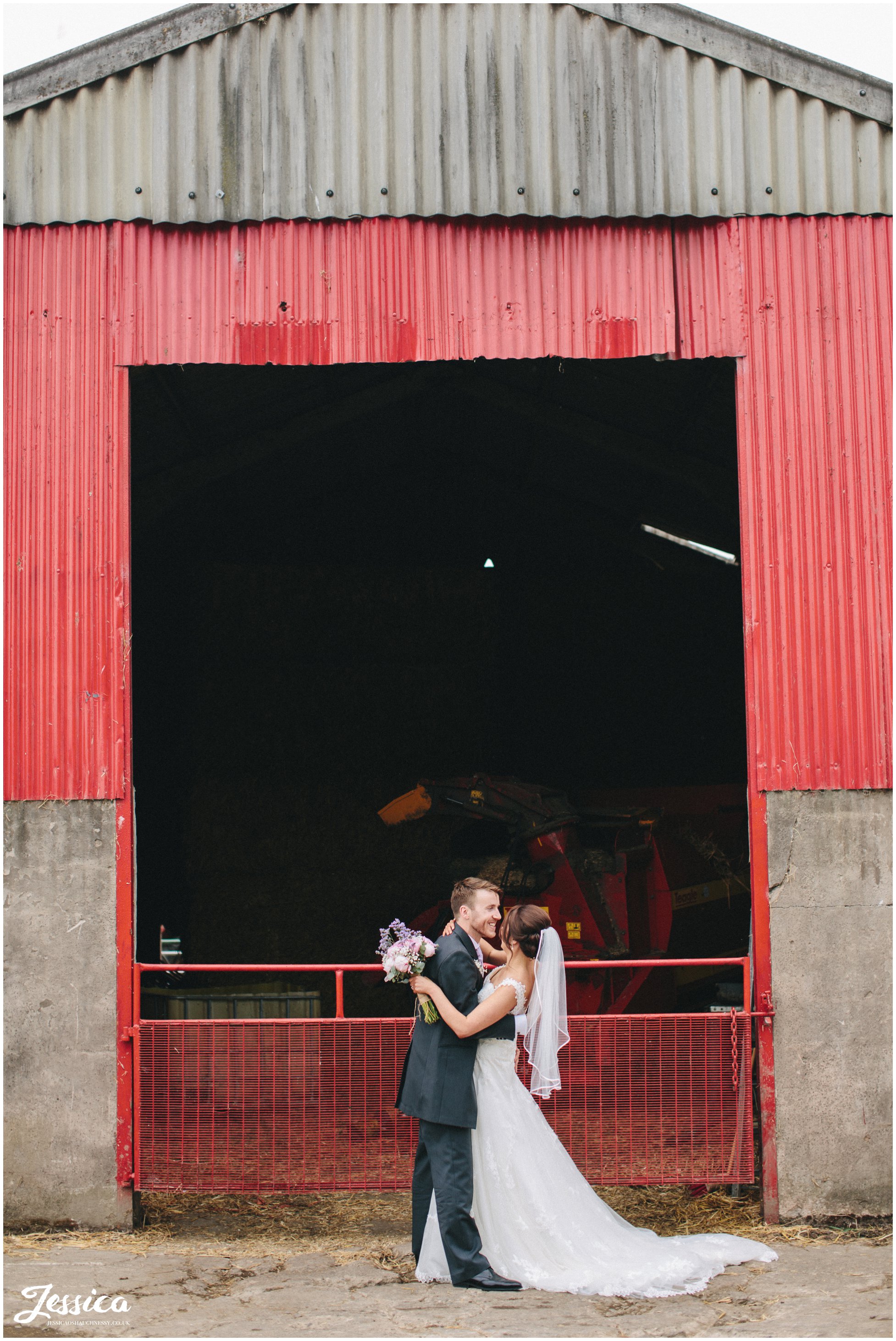 bride & groom kiss infront of farm gates at their cumbria wedding