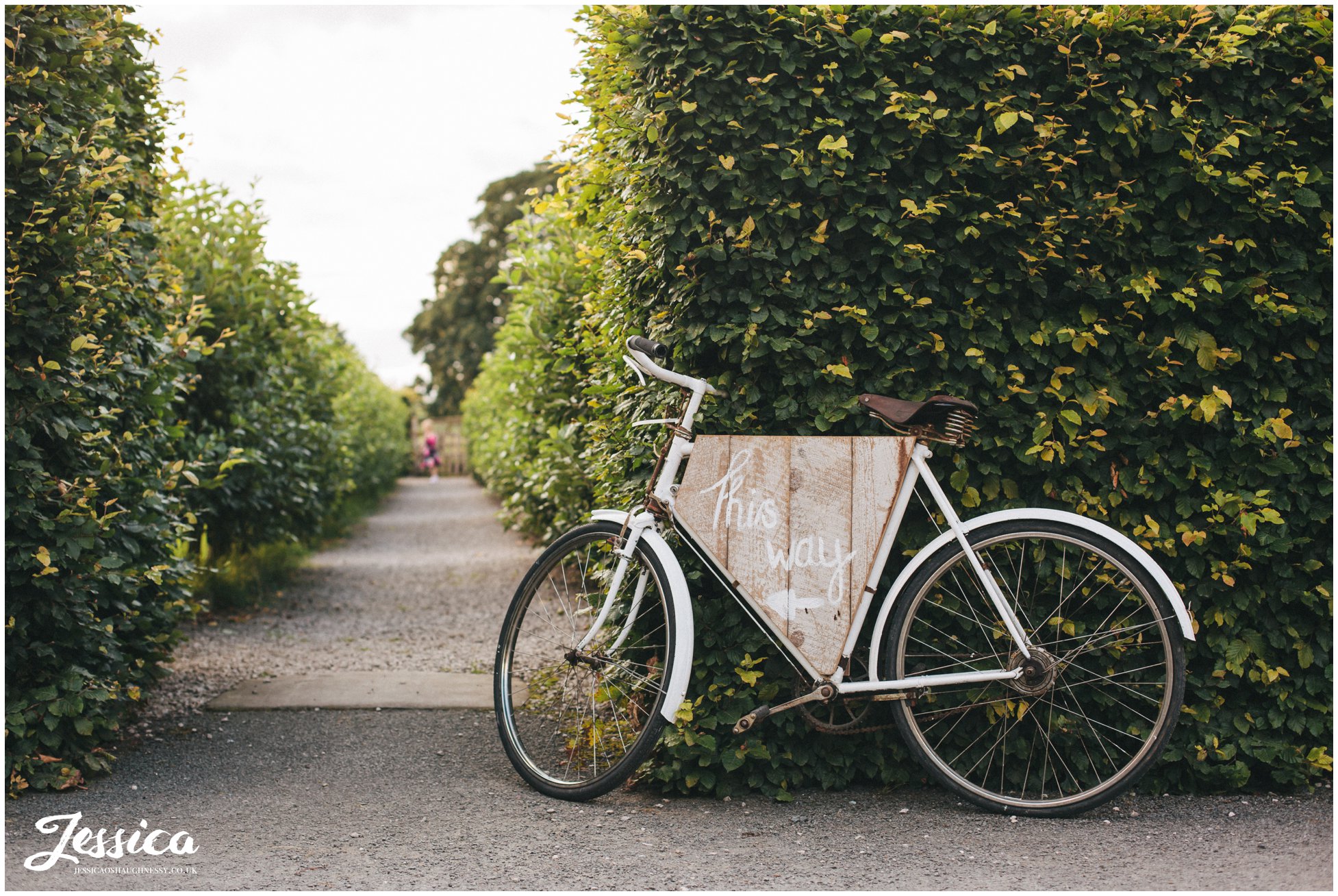 rustic, vintage bike with a 'this way' sign directs wedding guests to bank barn at askham hall