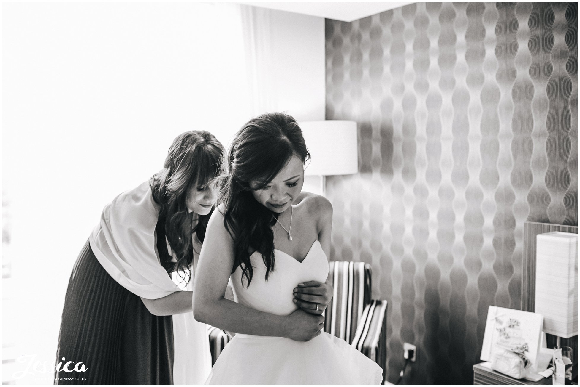 Manchester Wedding - Bridesmaid helps bride into her dress