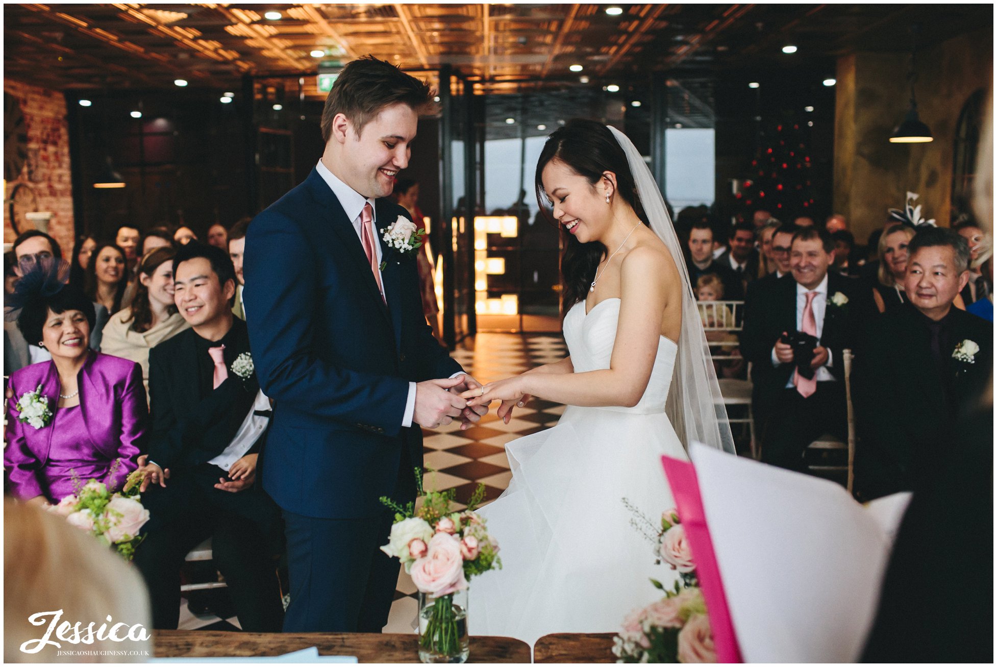 bride & groom exchanging rings - On The 7th Wedding Photography