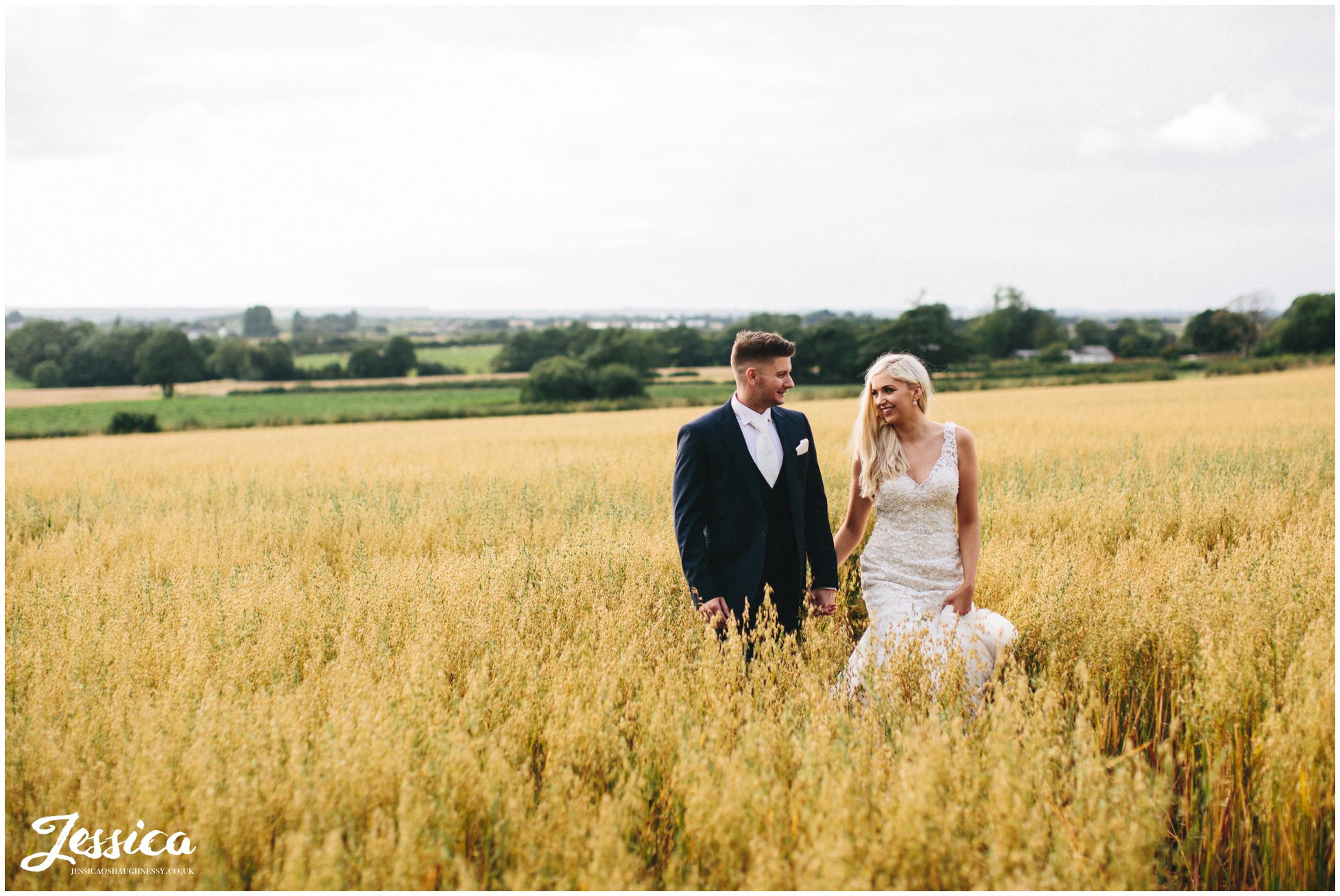 bride & groom walk through golden corn fields at their lancashire wedding