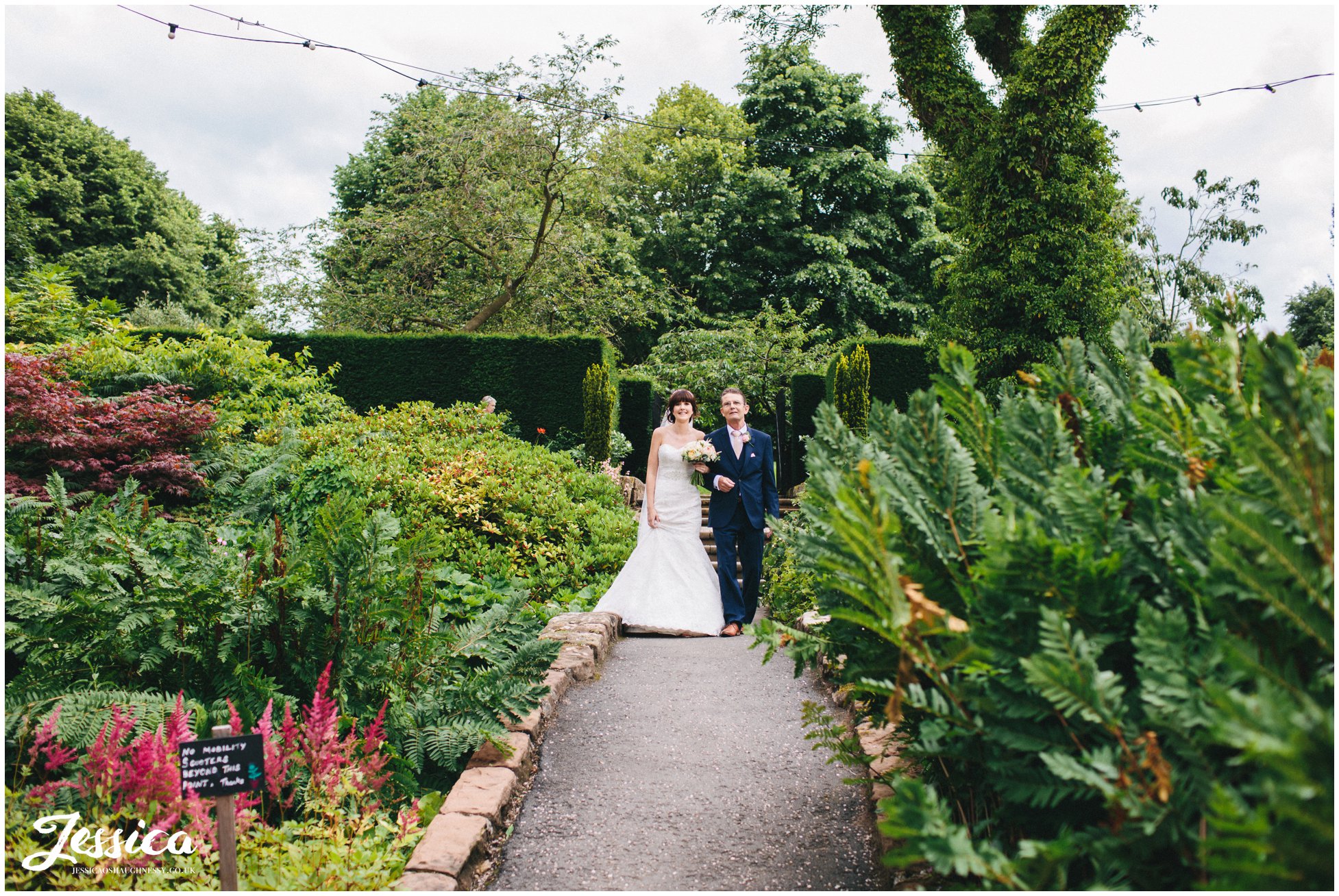 the bride & her father walk down the steps to her wedding ceremony at ness gardens on the wirral