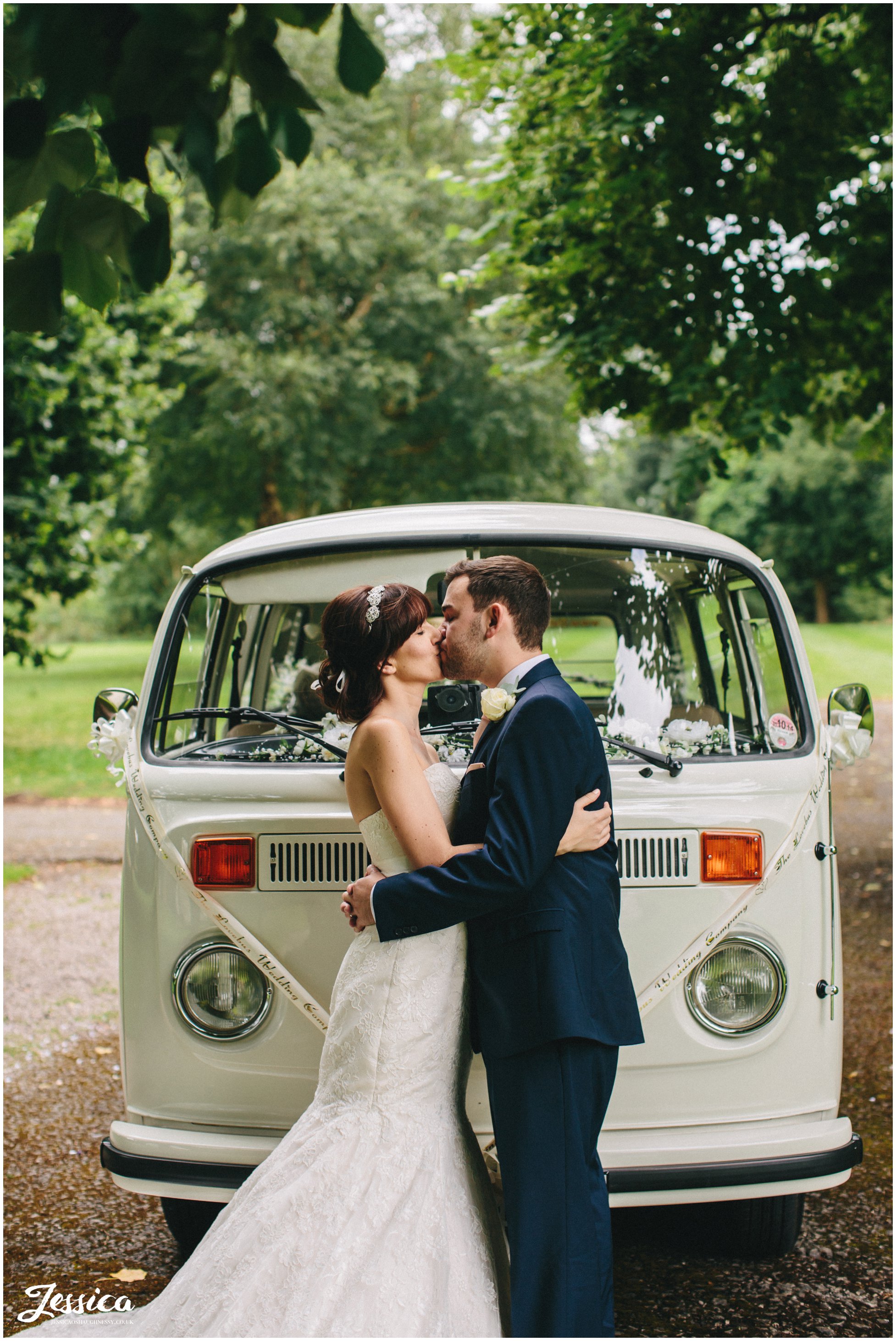 bride & groom share a kiss in ness gardens in front of their VW Camper on their wedding day