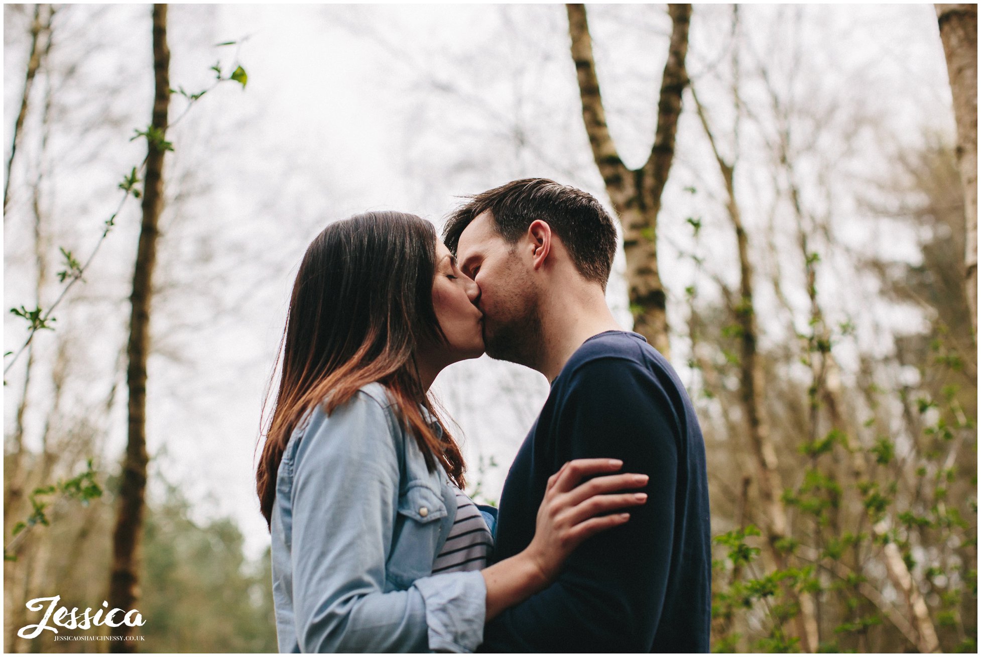 couple kiss during their pre-wedding shoot in the forest