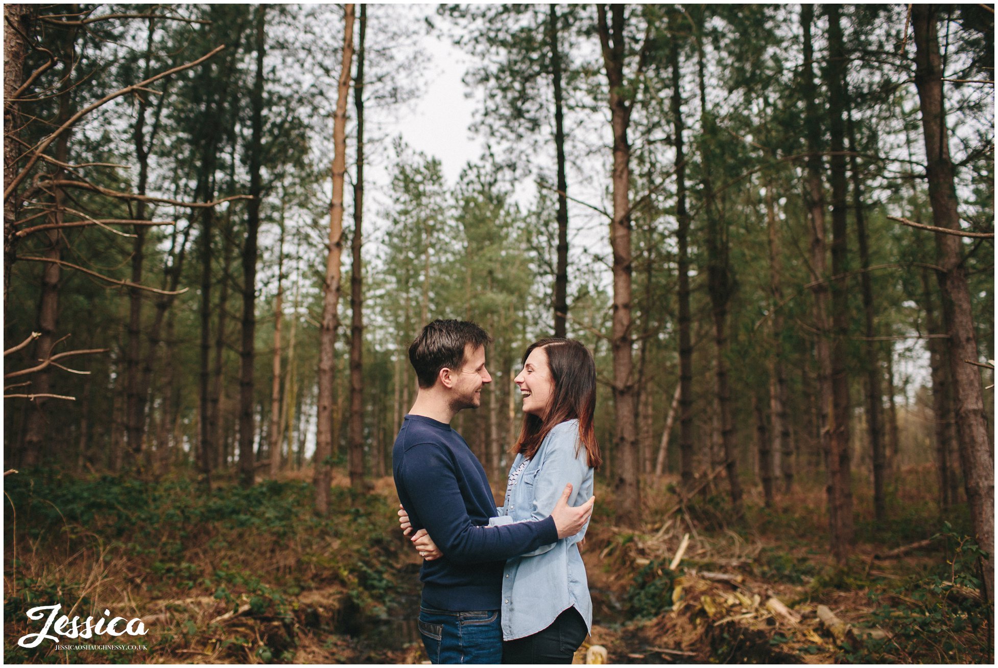 wide shot of couple laughing in the thick of the forest - delamere forest pre-wedding shoot