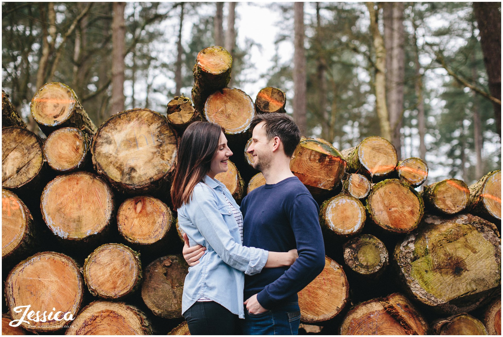 couple stand in front of chopped down trees - cheshire wedding photographer