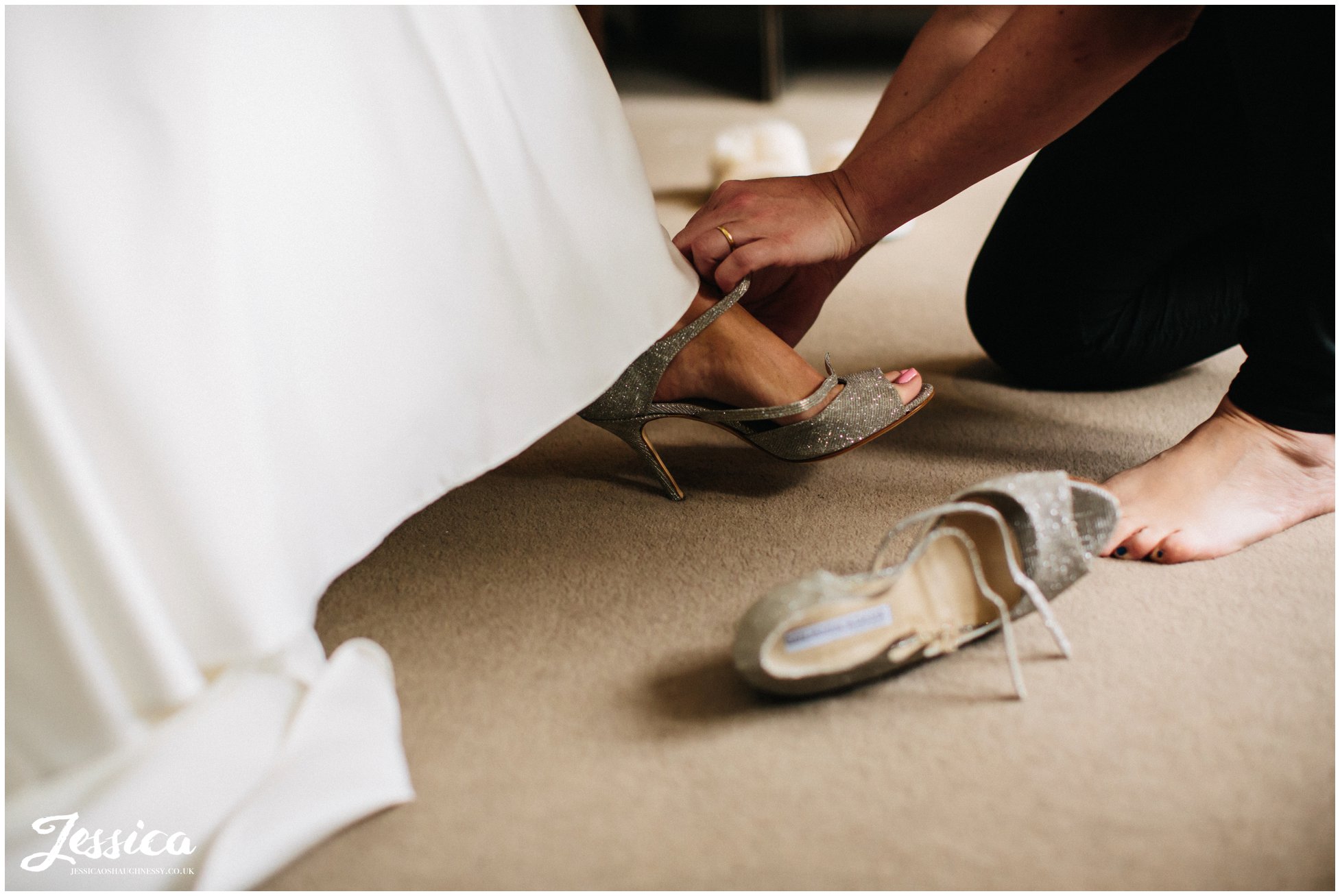 bridemaid slips on brides shoes for her on the morning of her wirral wedding