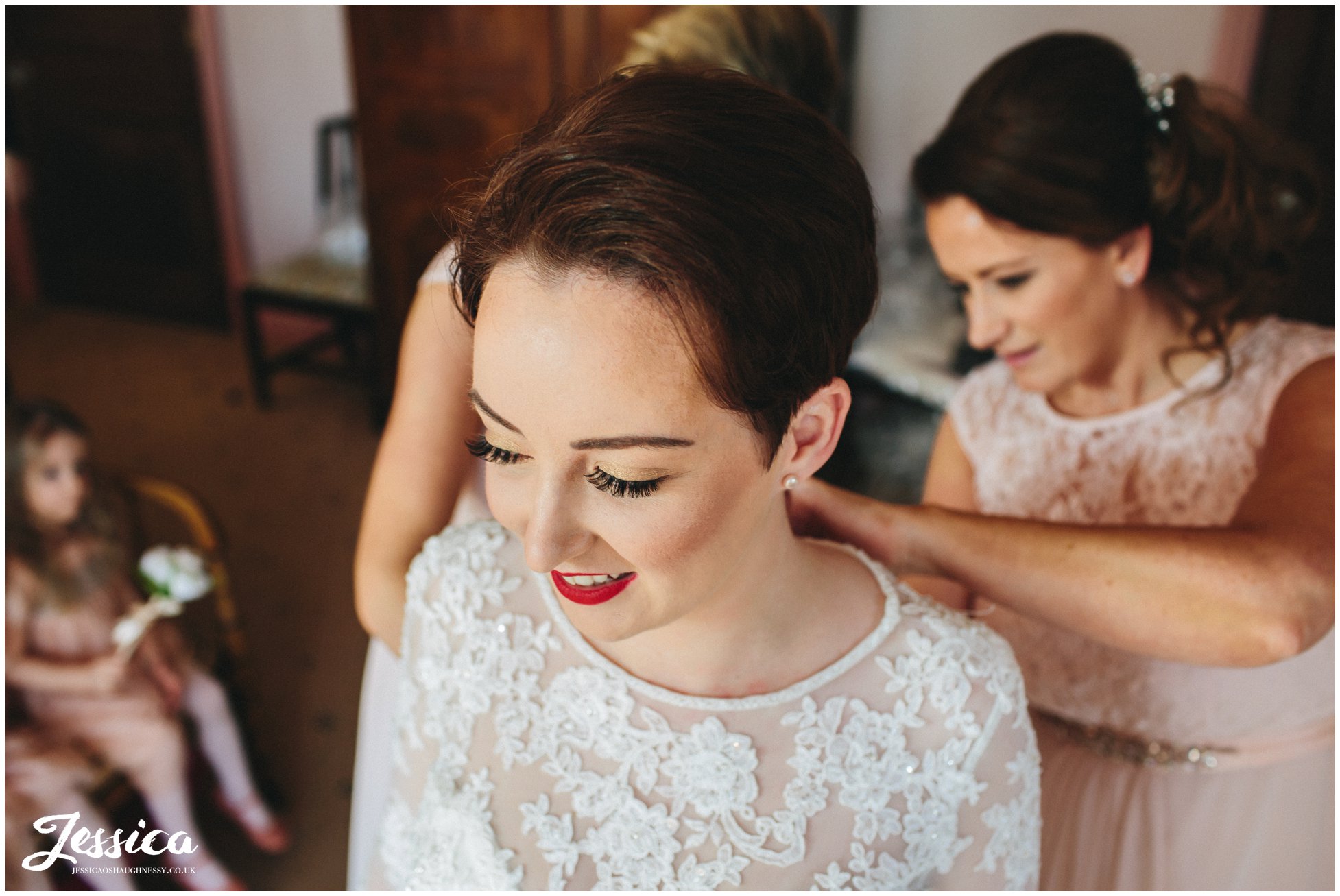 the bride is helped into her wedding dress by her bridesmaids - wirral wedding photographer