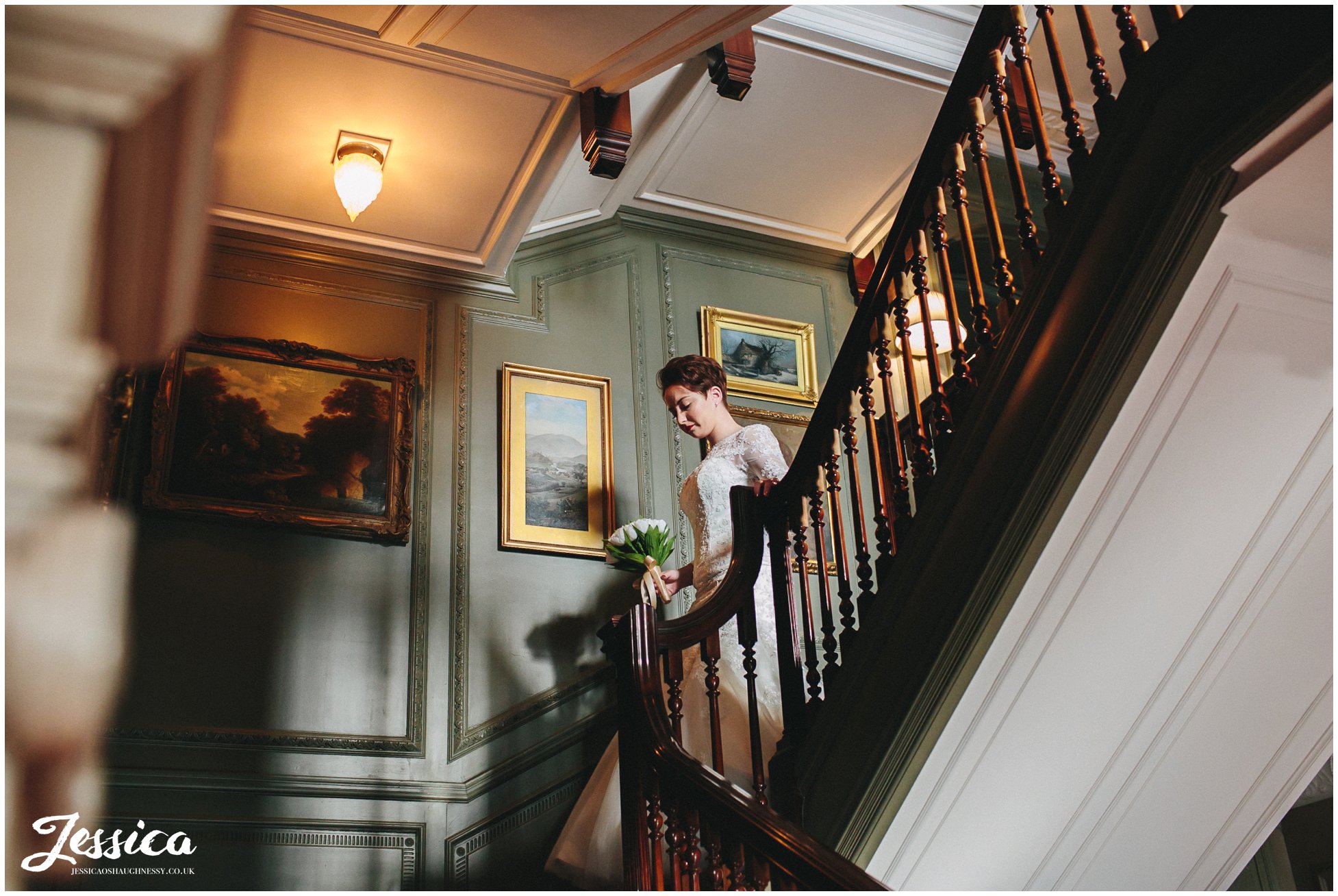 bride walks down the stairs to her ceremony in thornton manor, wirral
