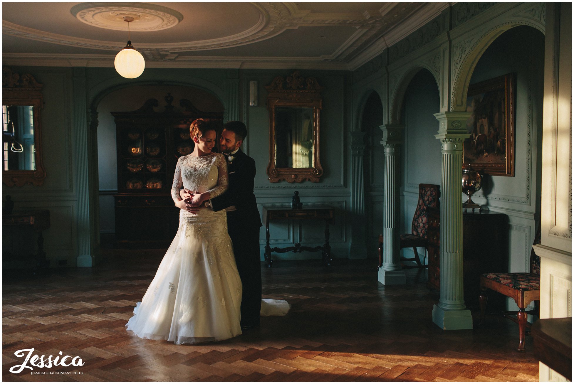 interior shot of the bride & groom stood in light pouring through the window at thornton manor
