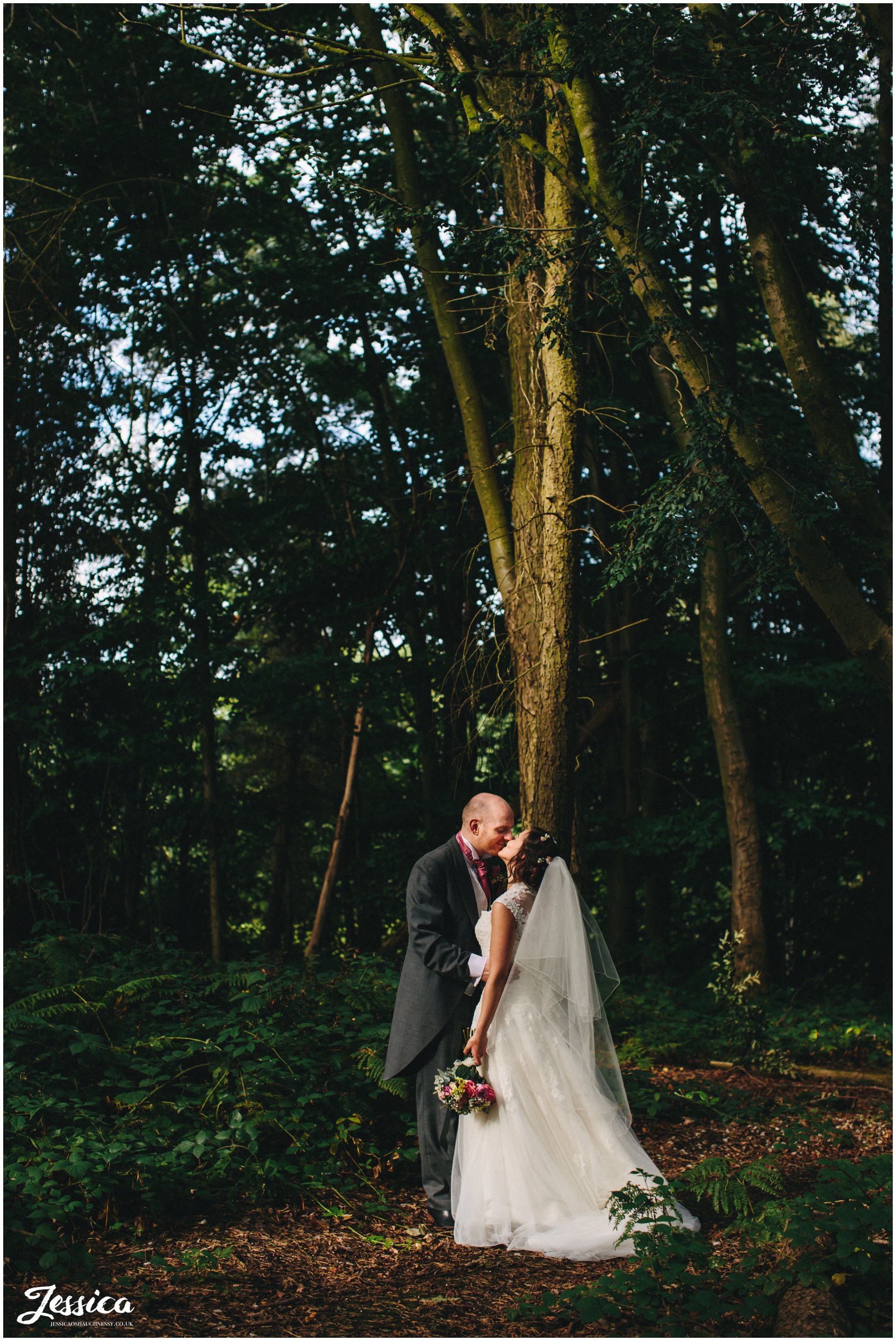 bride & groom kissing in the woodland in chester
