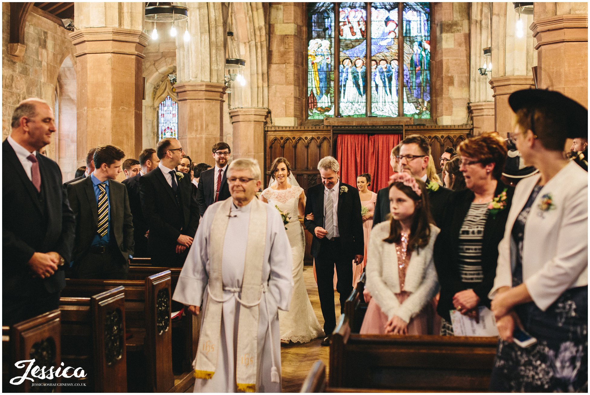 bride walks down the aisle at the north wales church in hawarden