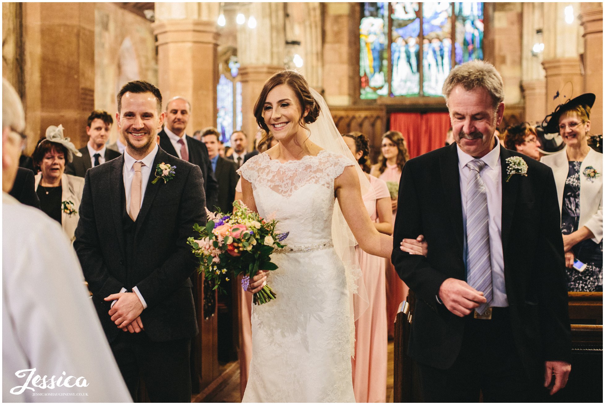 bride links arms with her father during the wedding ceremony, st deiniols church