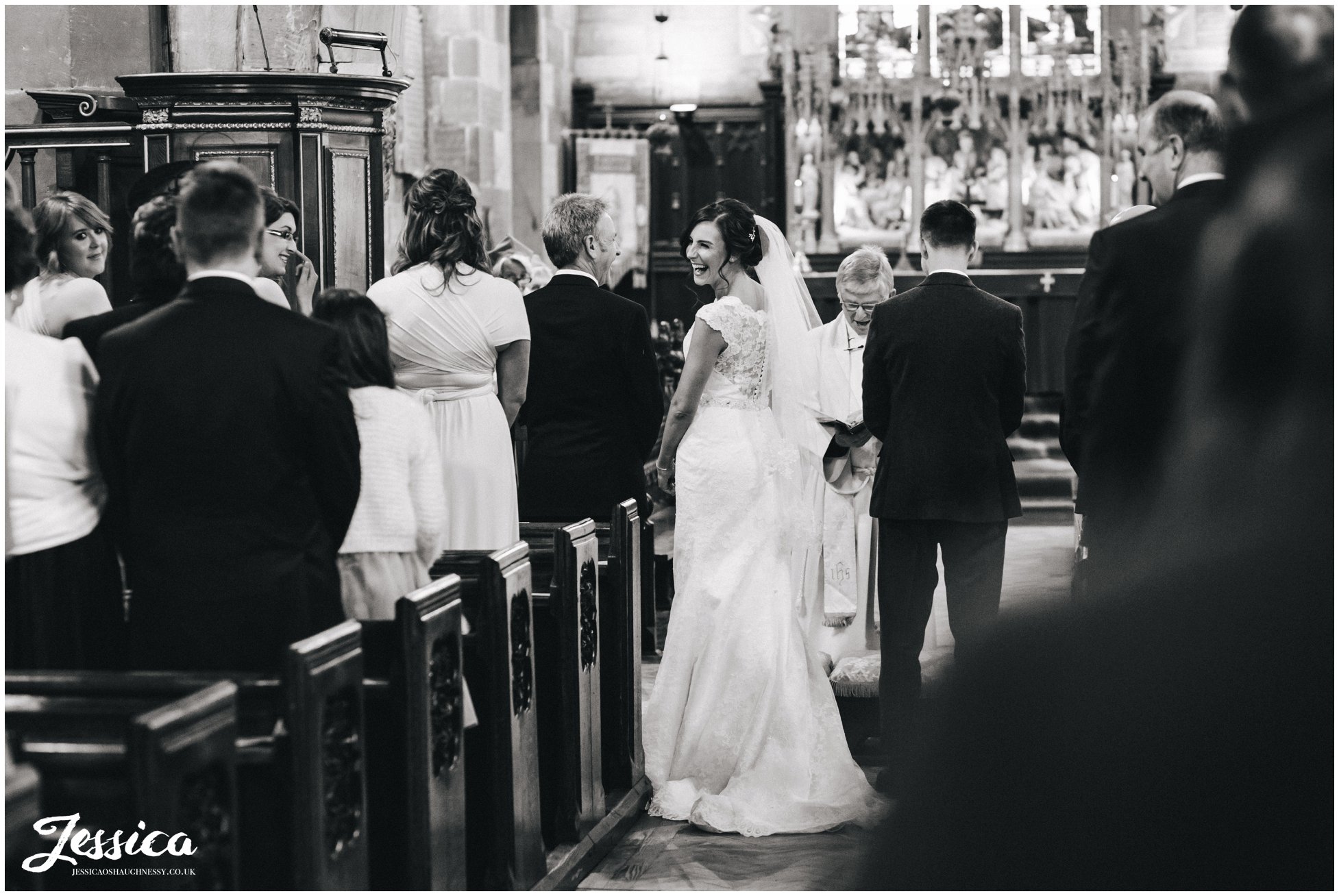 black and white photograph of the bride laughing during the ceremony at st deiniols church, north wales