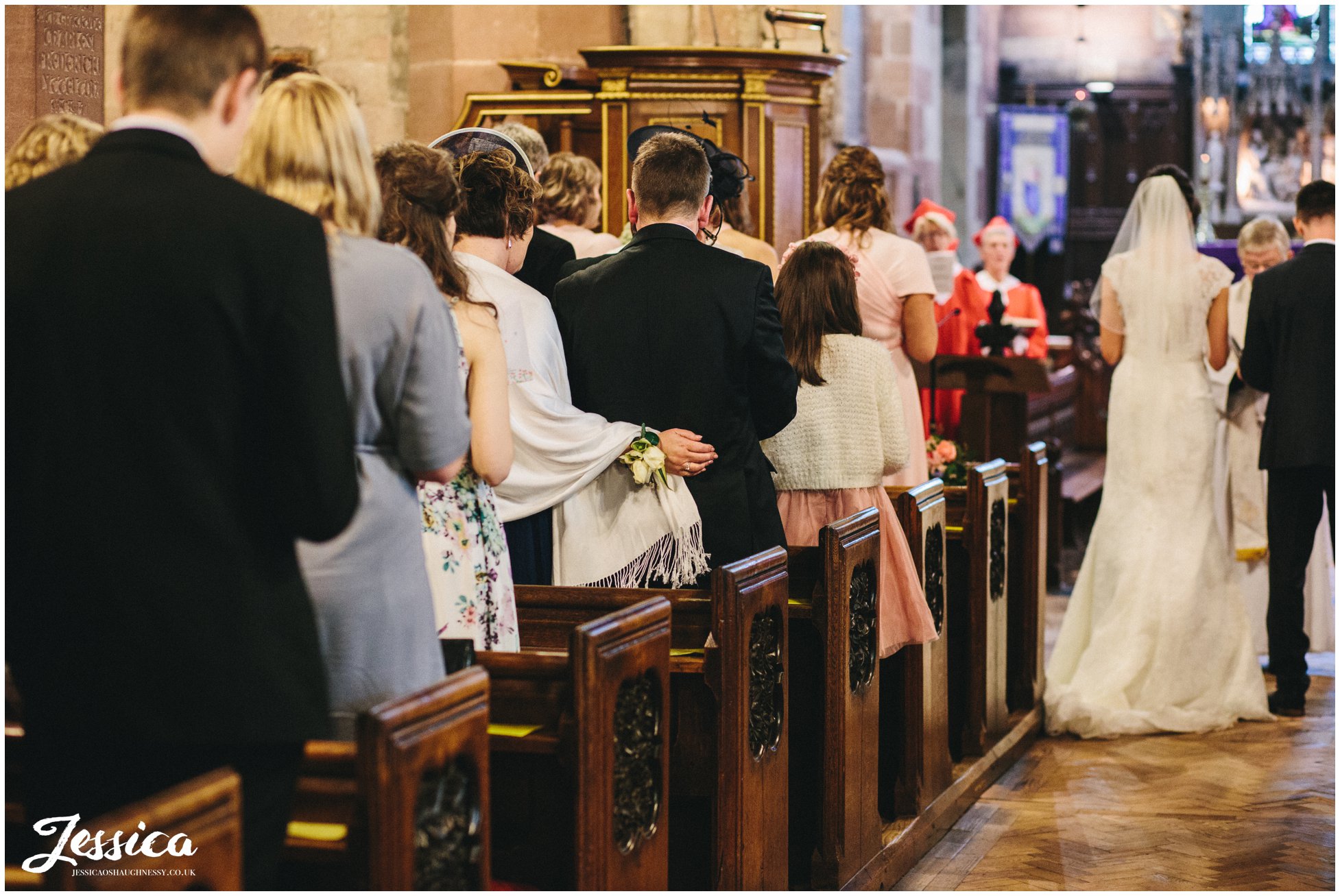guest puts her arm around her partner during the wedding ceremony
