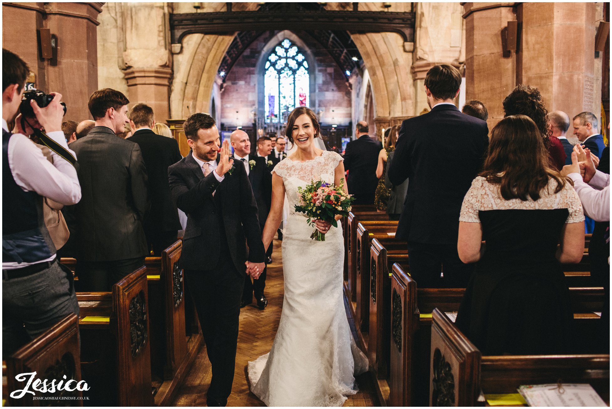 newly wed's walk out of the church after their ceremony - st deiniols in hawarden