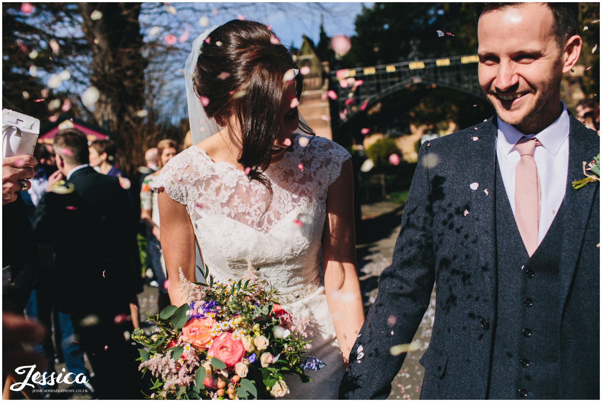 bride and groom are showered in confetti on a sunny day in north wales