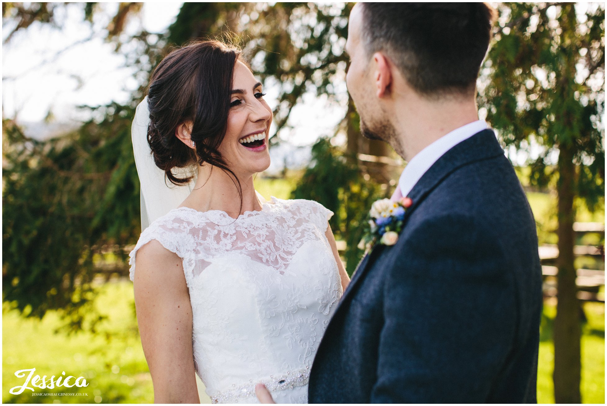 bride laughs stood in front of trees at a north wales wedding