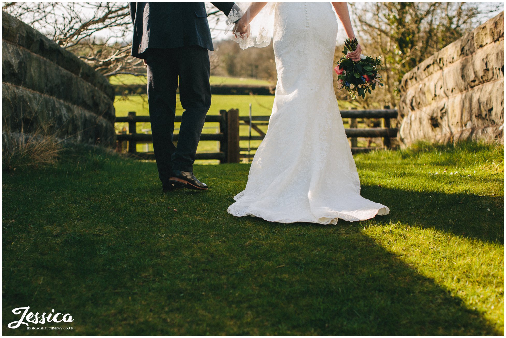 bride and groom hold hands walking over the bridge at tower hill barns