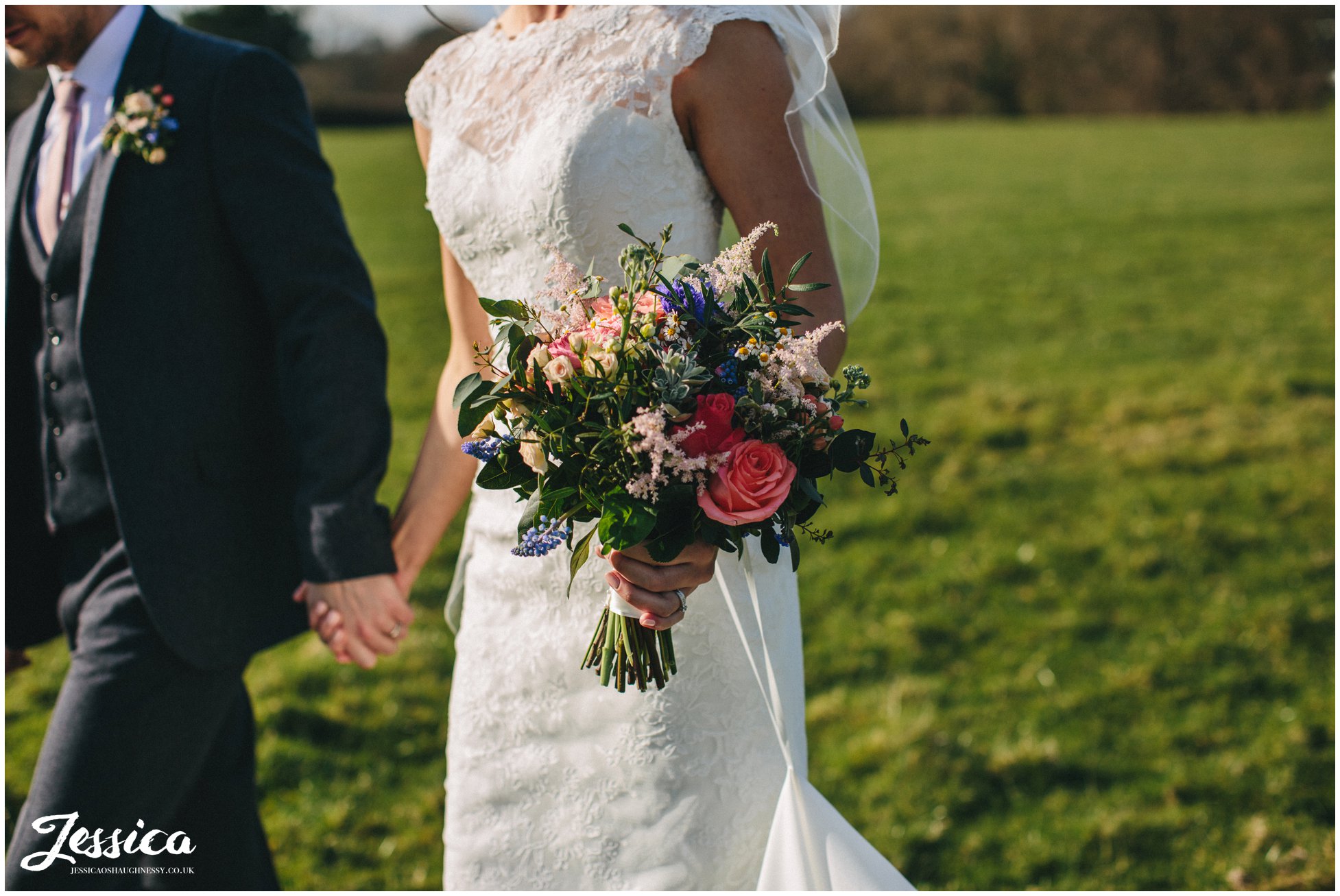 close up of bridal bouquet as she walks through a field with her husband - tower hill barns wedding photography