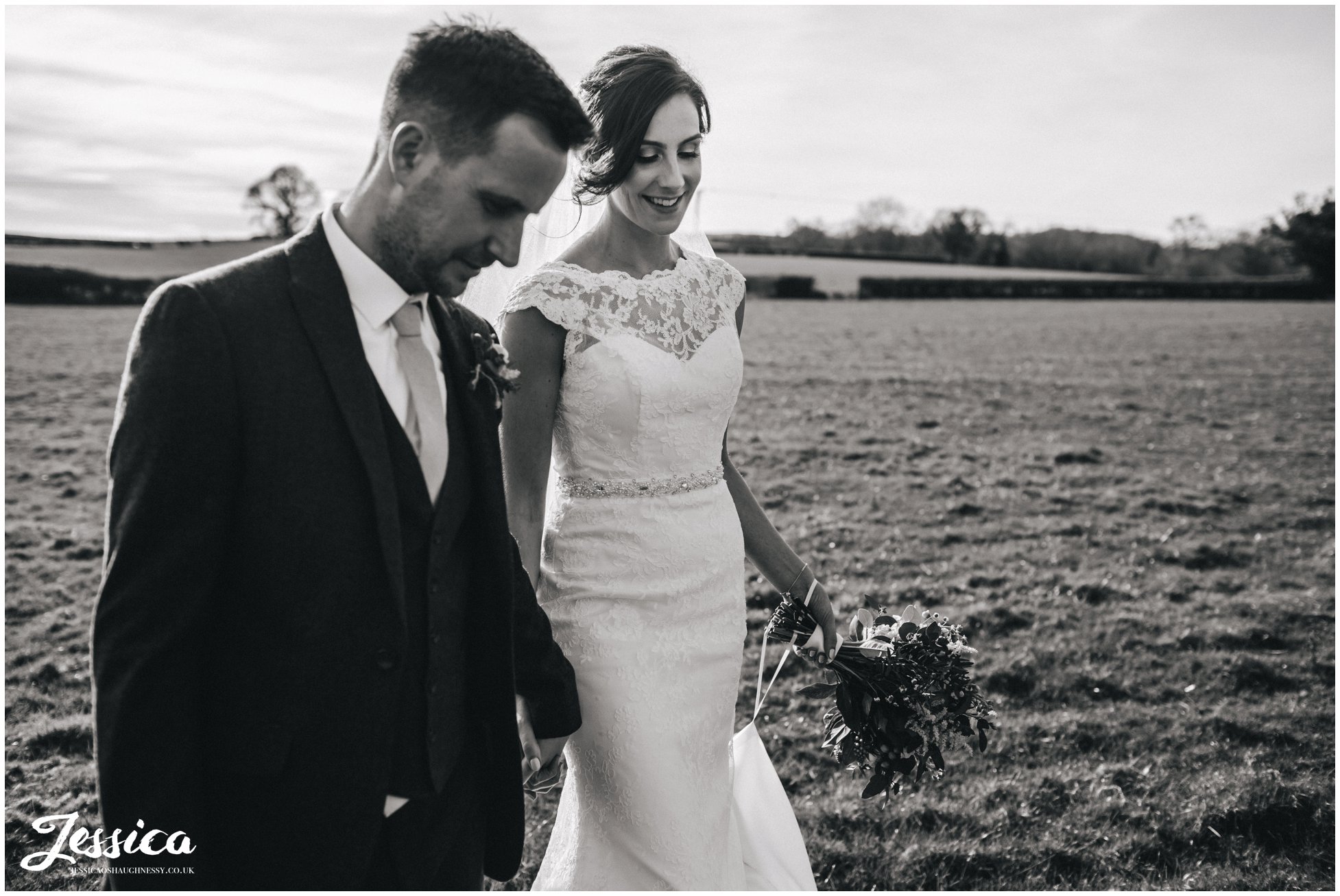 newly wed's wander through field in north wales - black and white
