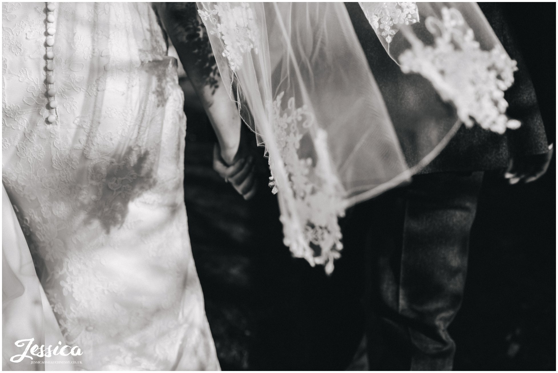 detail shot of the brides veil as she holds grooms hand
