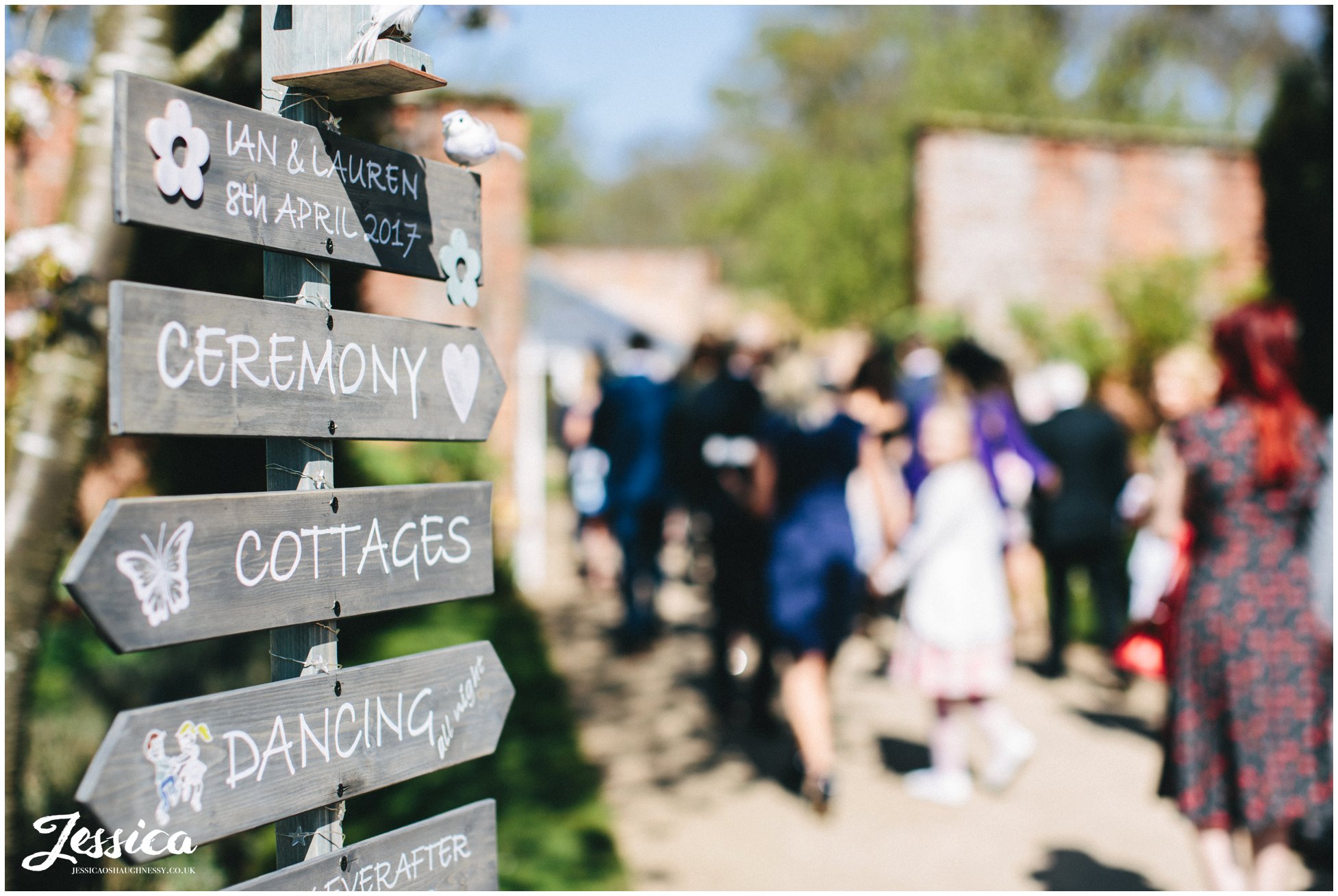 rustic wedding sign points guests to the glass house ceremony