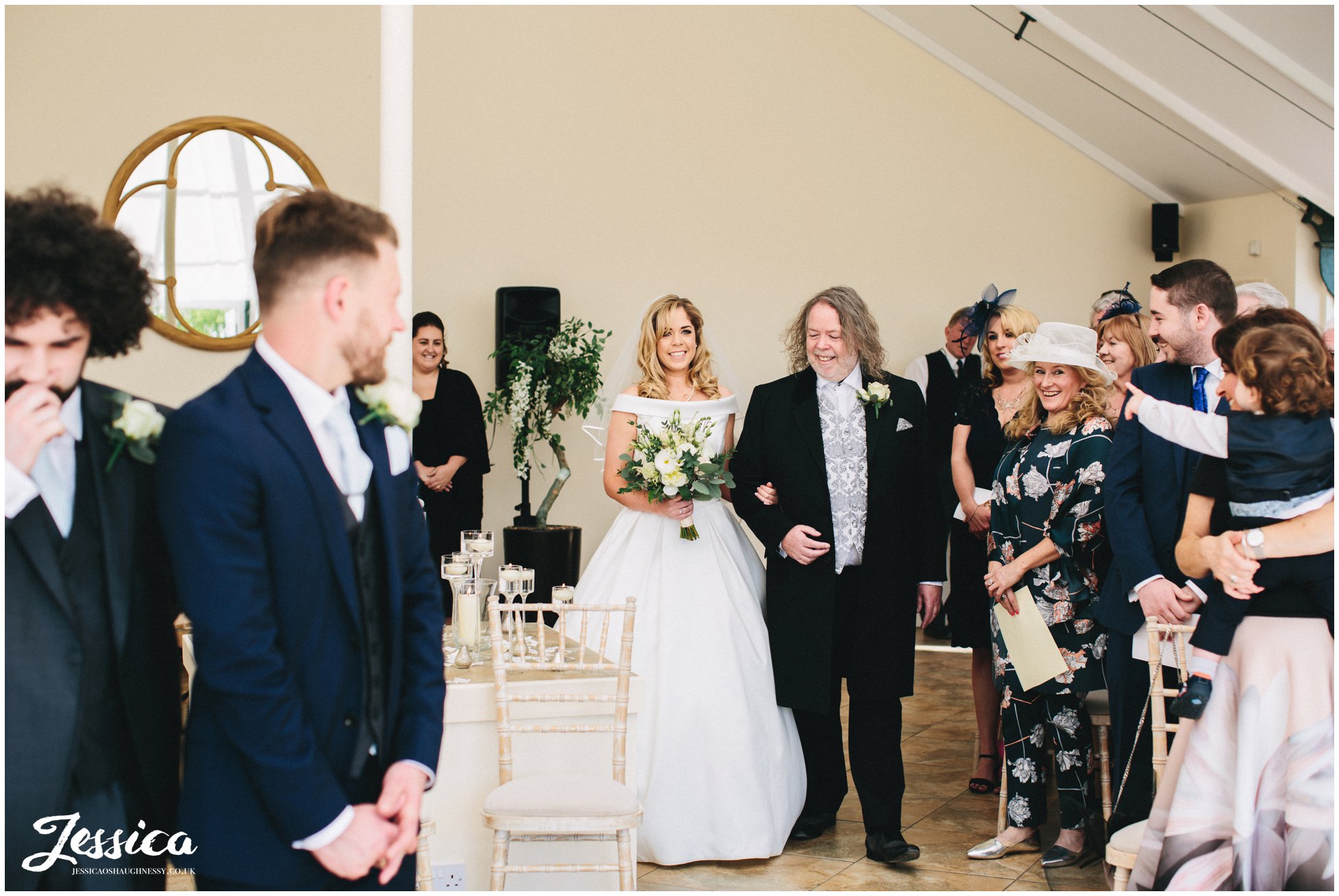 bride enters the glass house and walks down aisle to her groom
