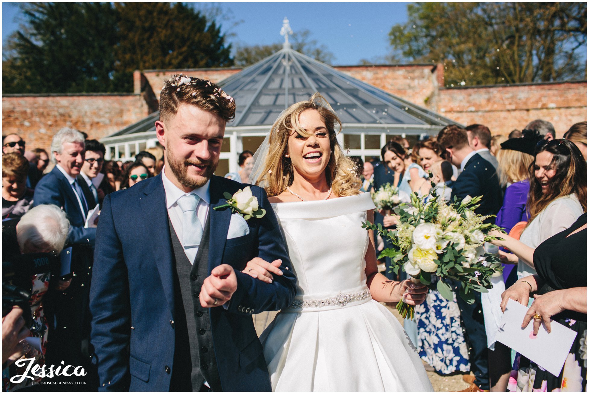 couple laugh as they're showered in confetti