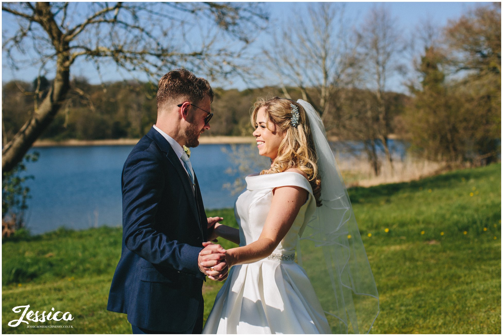 newly wed's hold hands by the lake at Combermere Abbey