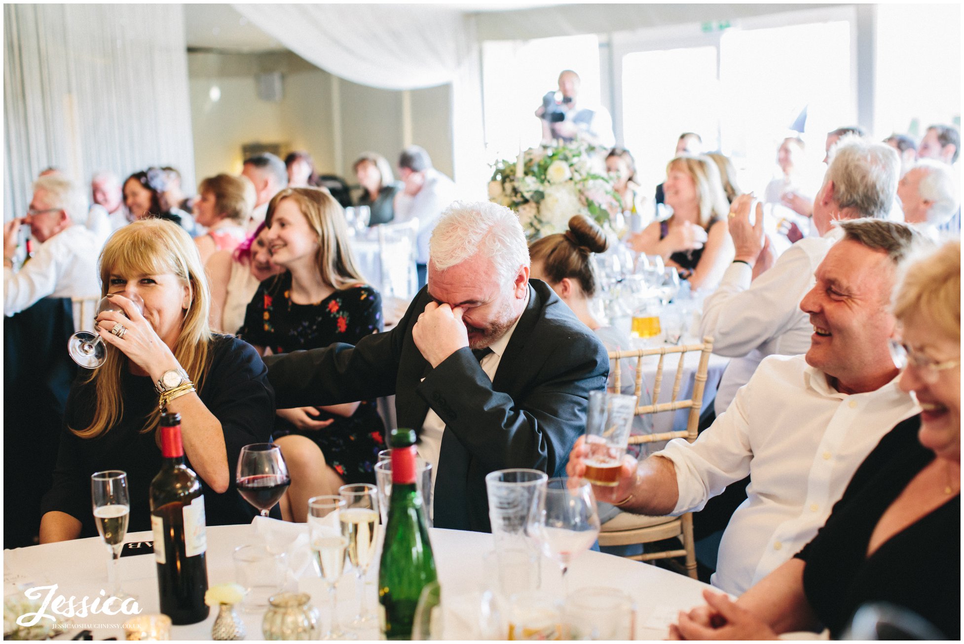 guest laughs into hands during the speeches at Combermere Abbey